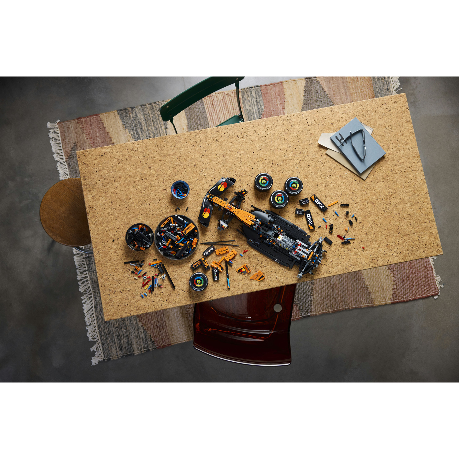 Un'auto di Formula 1 LEGO smontata giace su un tavolo di legno circondata da pezzi e ruote.