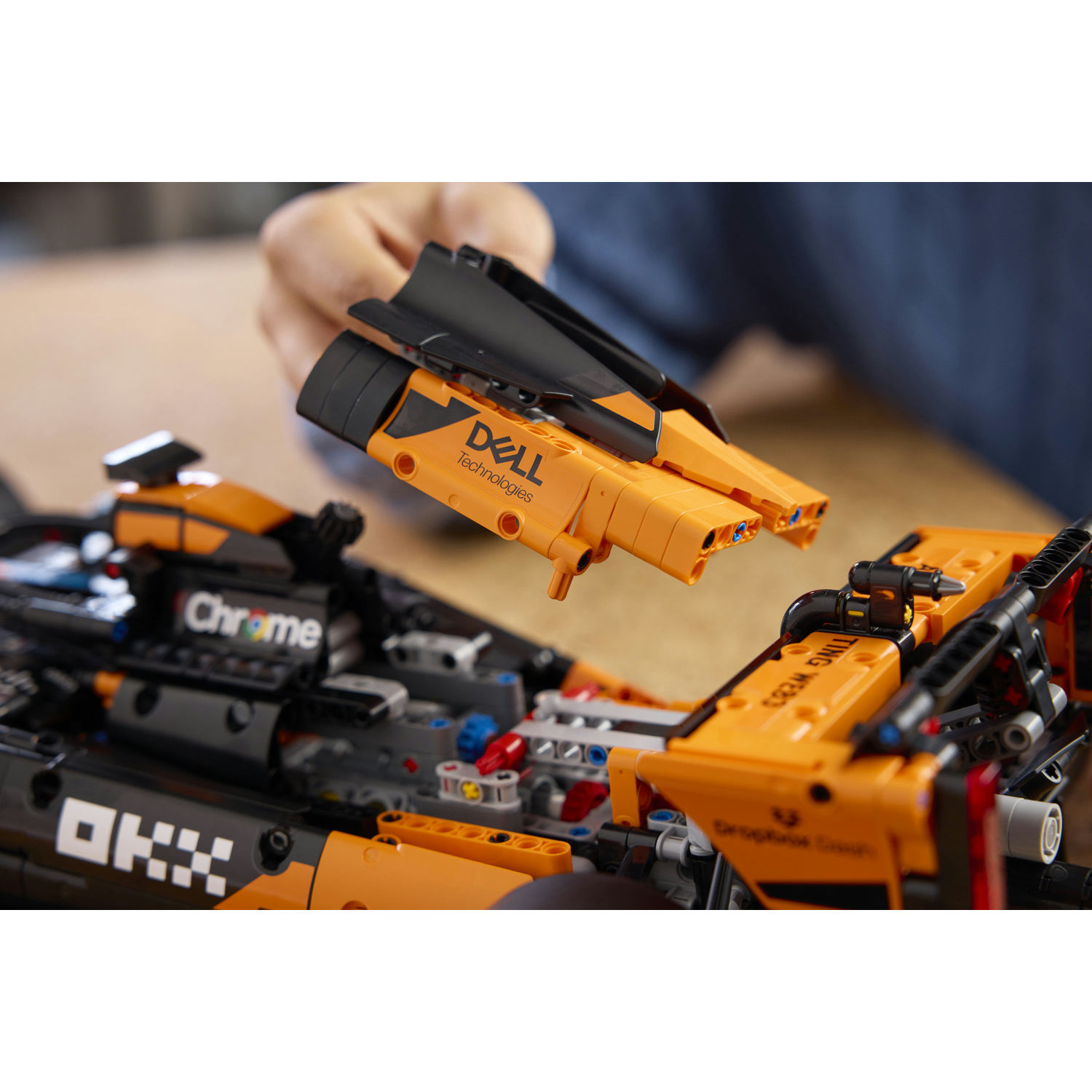 Persona costruisce auto da corsa Lego arancione con logo Dell.