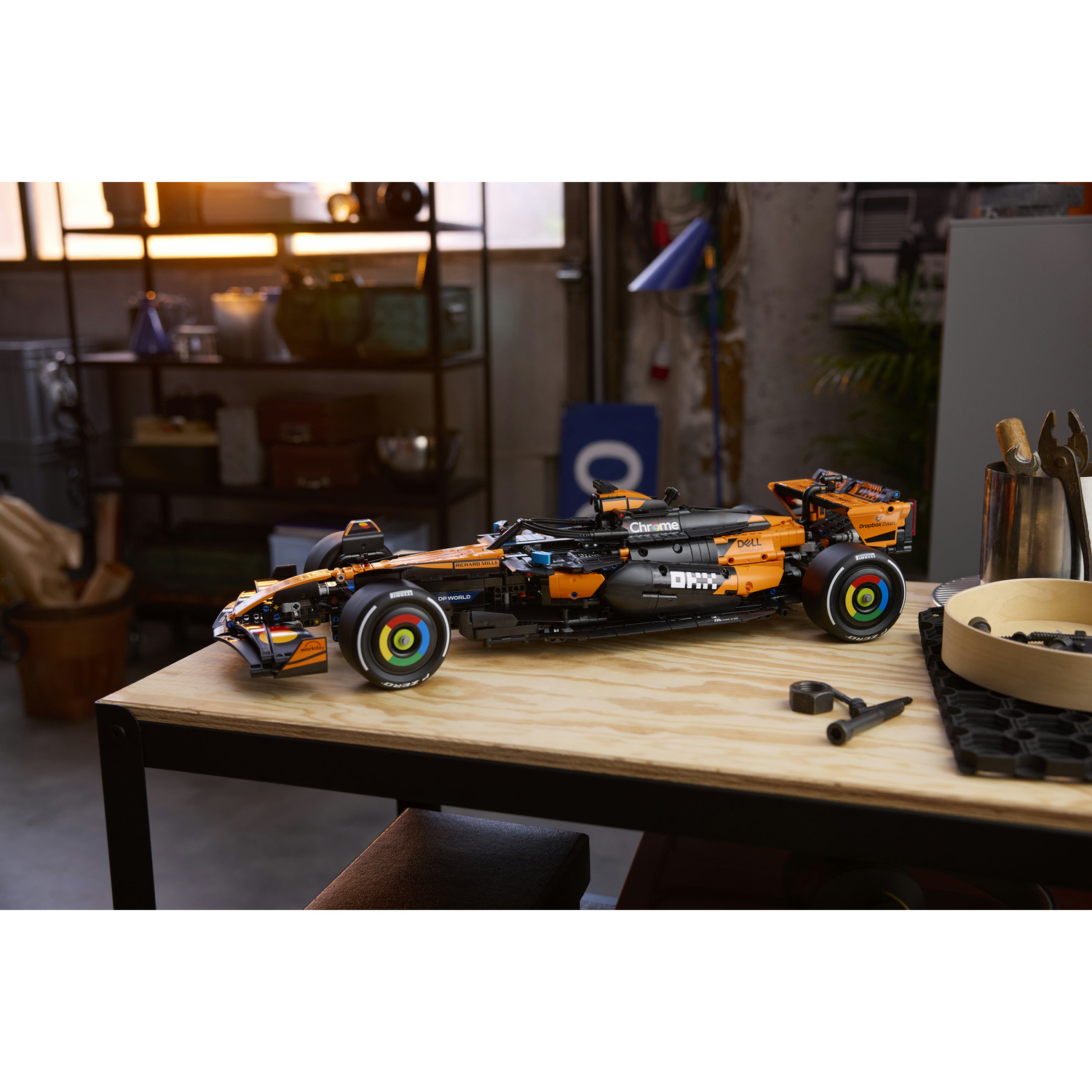 Un'auto da corsa Lego arancione e nera su un tavolo di legno in un'officina.
