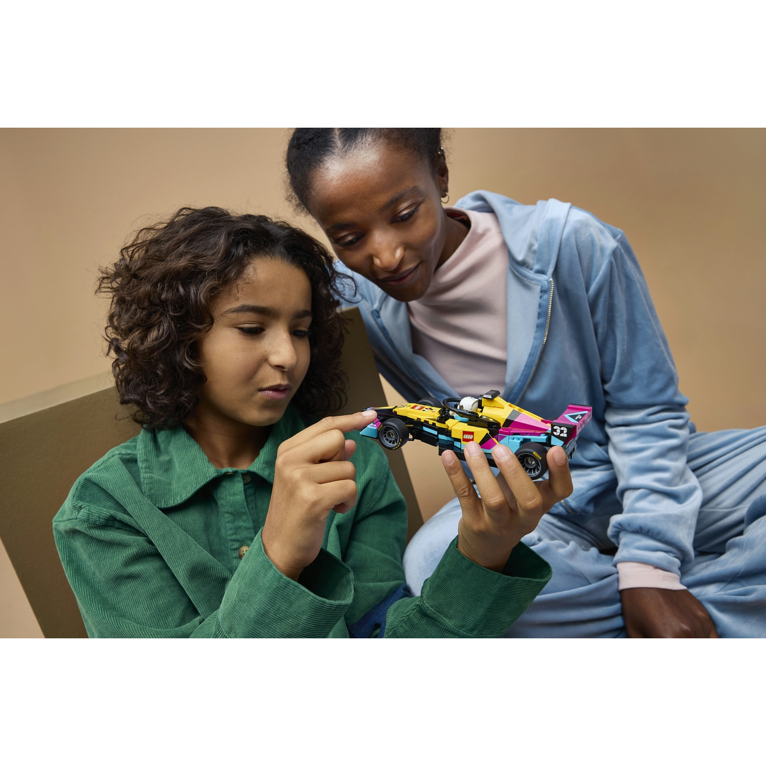 Un bambino tiene una colorata auto da corsa Lego, una donna guarda.