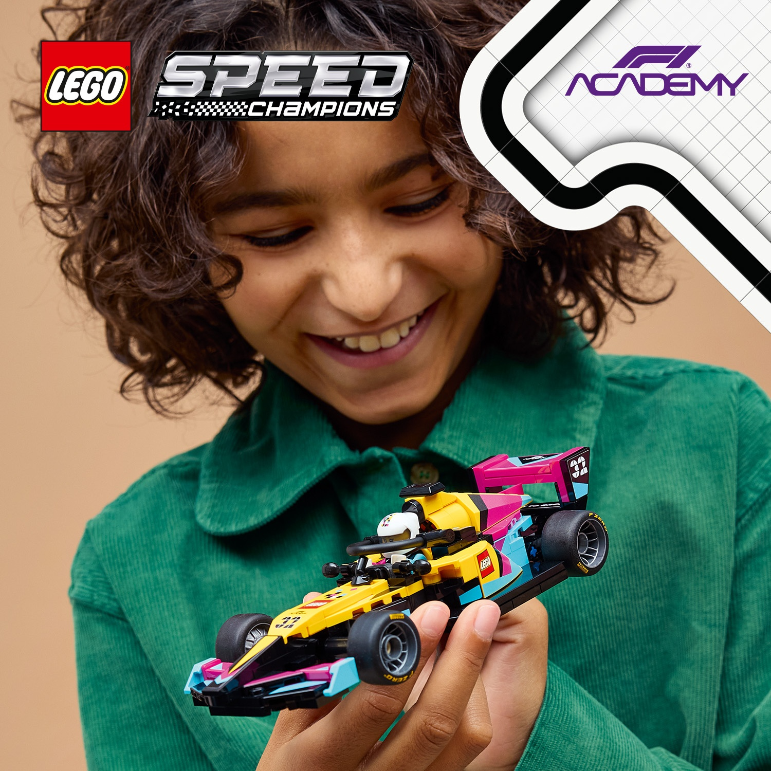 Bambino tiene auto da corsa LEGO Formula 1 gialla con accenti rosa e blu.
