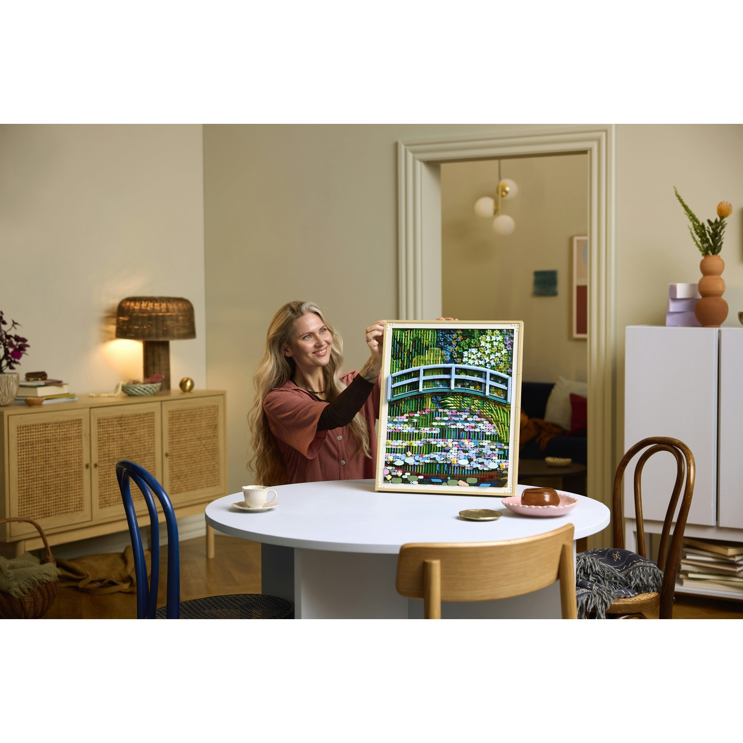 Donna tiene un quadro di un ponte giapponese su ninfee. Stanza accogliente.