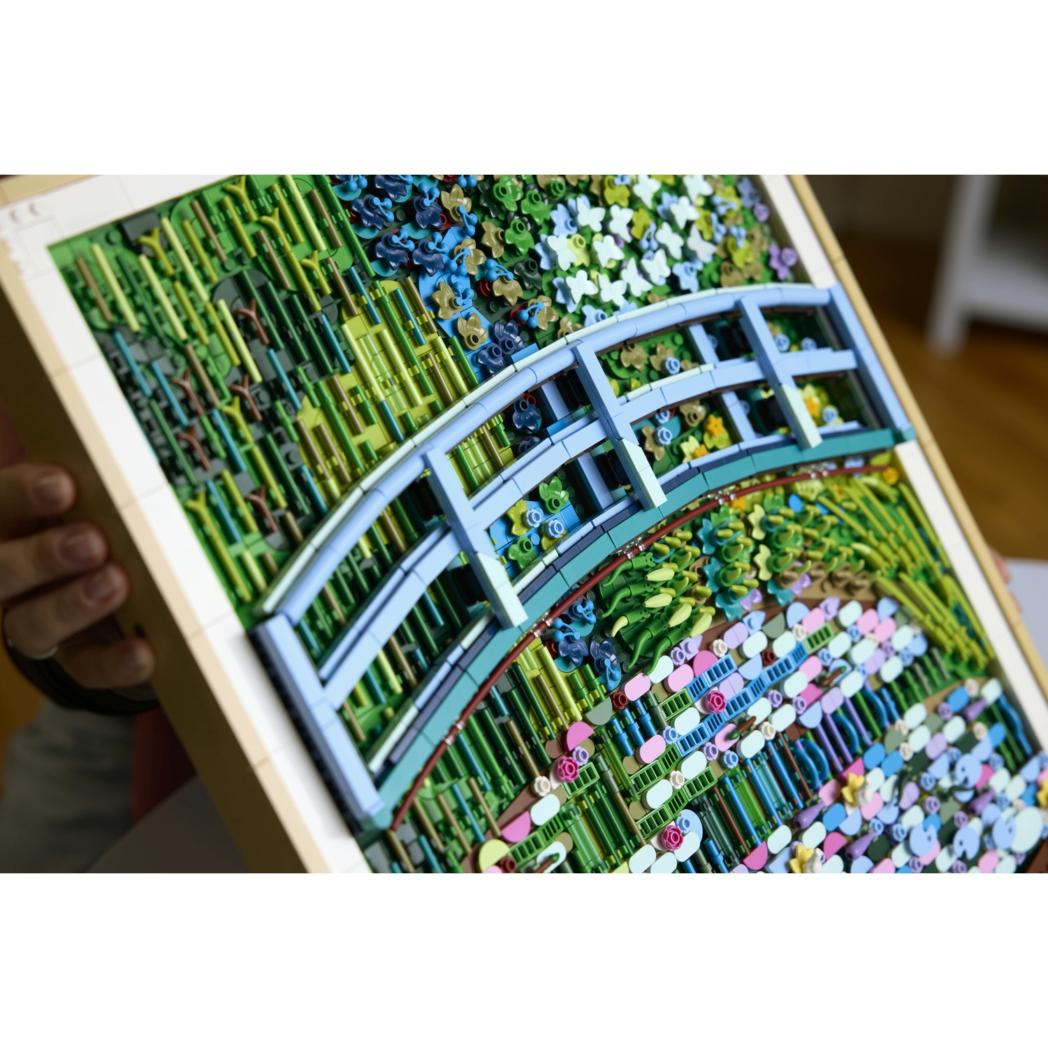 Un modello Lego di un giardino con ponte blu e fiori colorati.