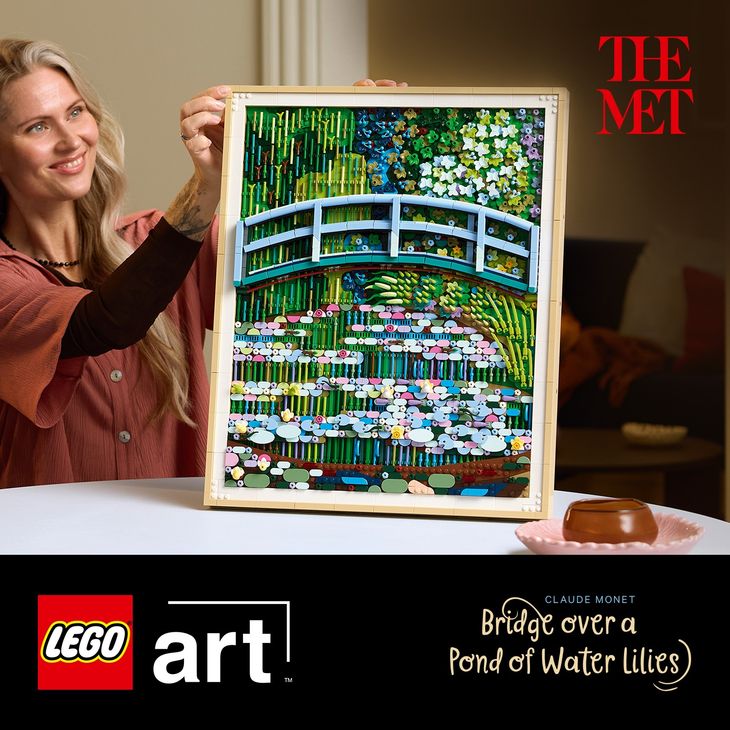 Una donna tiene un mosaico LEGO di 'Ponte su uno stagno di ninfee' di Monet.