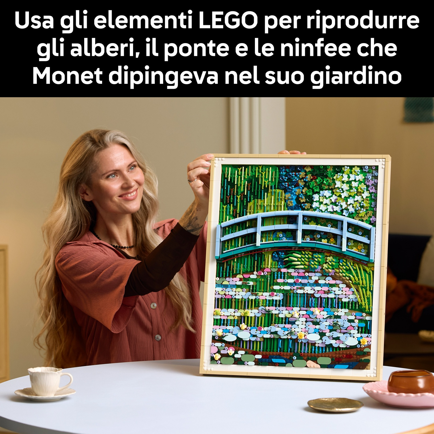 Donna tiene quadro LEGO Giardino di Monet: ponte, alberi, ninfee.