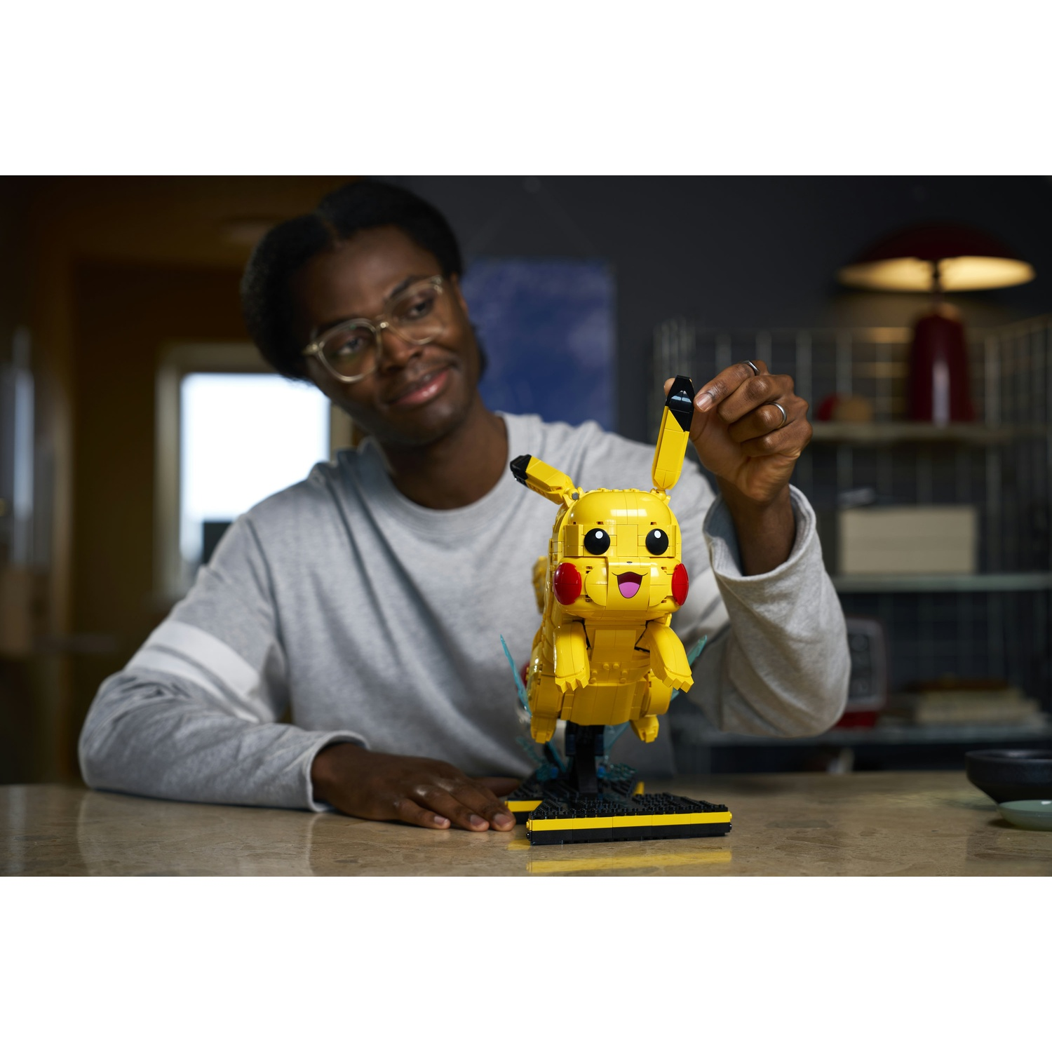 Un uomo costruisce un personaggio Pikachu giallo LEGO con base elettrica.