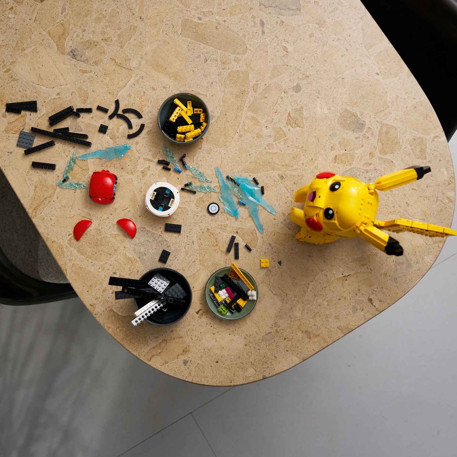 Pezzi Lego colorati, tra cui un Pikachu giallo, sparsi su un tavolo di marmo.