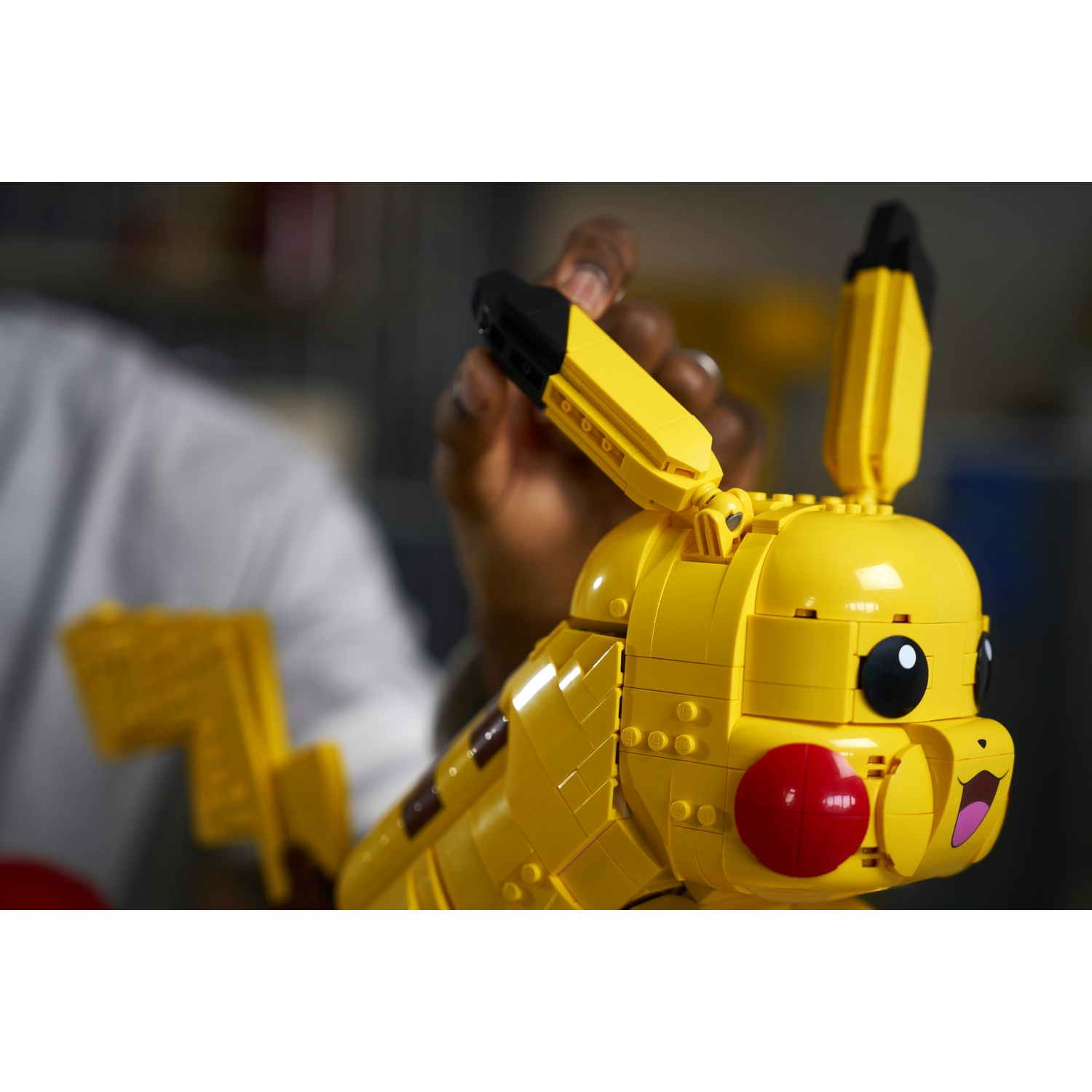 Un Pikachu giallo Lego viene assemblato da mani.