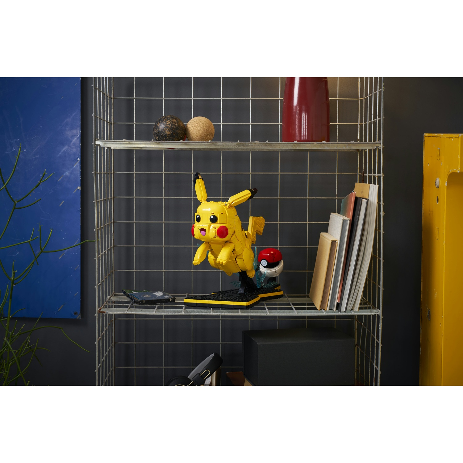 Modello LEGO Pikachu giallo su mensola con libri e sfere decorative.