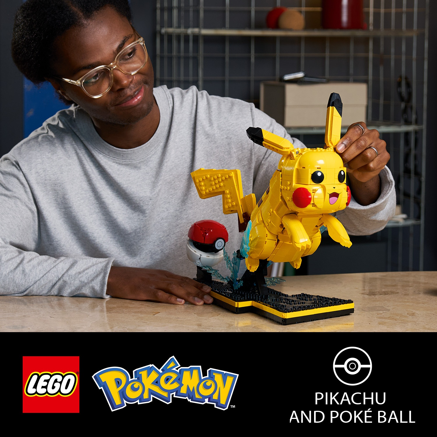 Uomo costruisce figura Lego Pikachu gialla con Poké Ball su piedistallo.