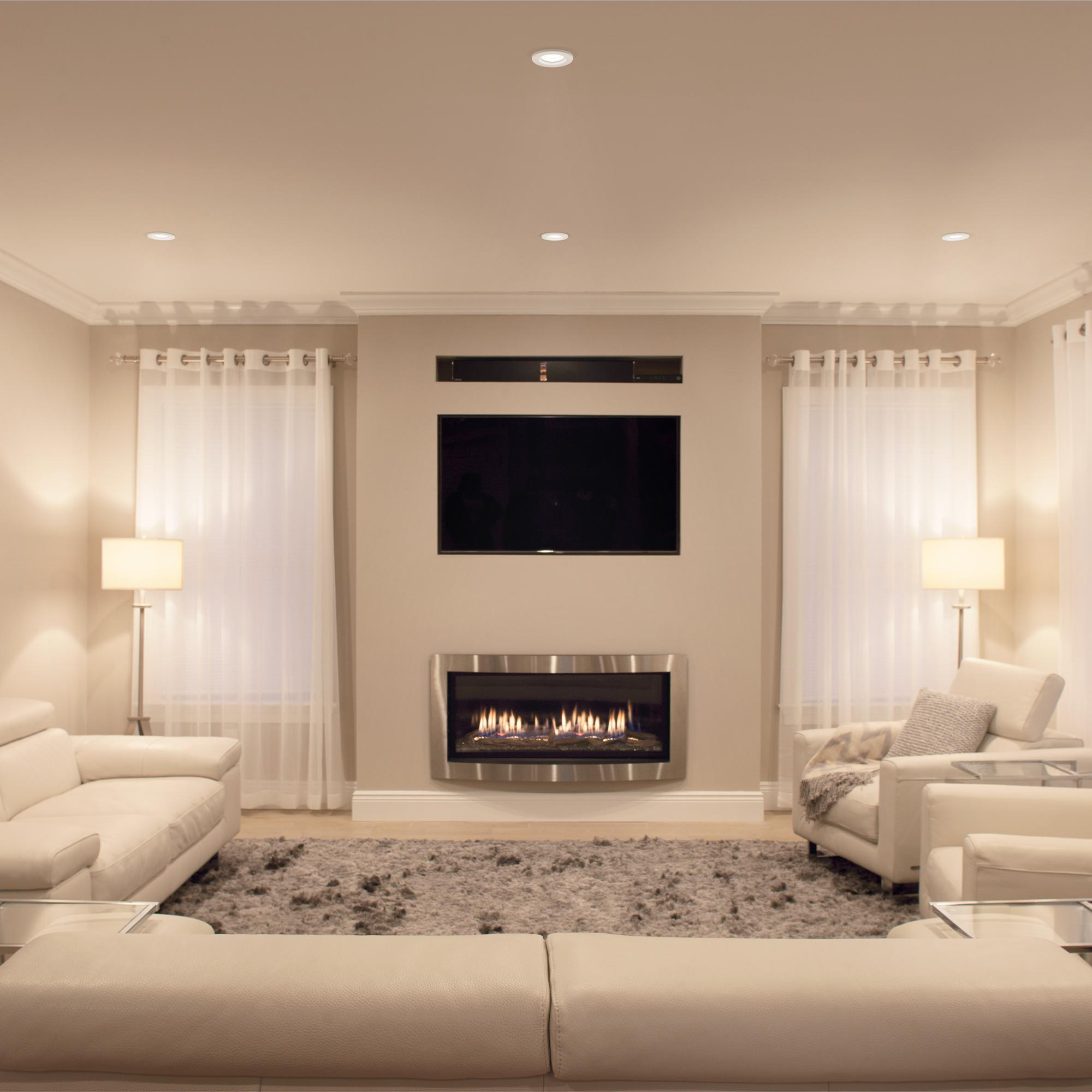 Ein Wohnzimmer mit Kamin, Fernseher, weißen Sofas und Teppich.