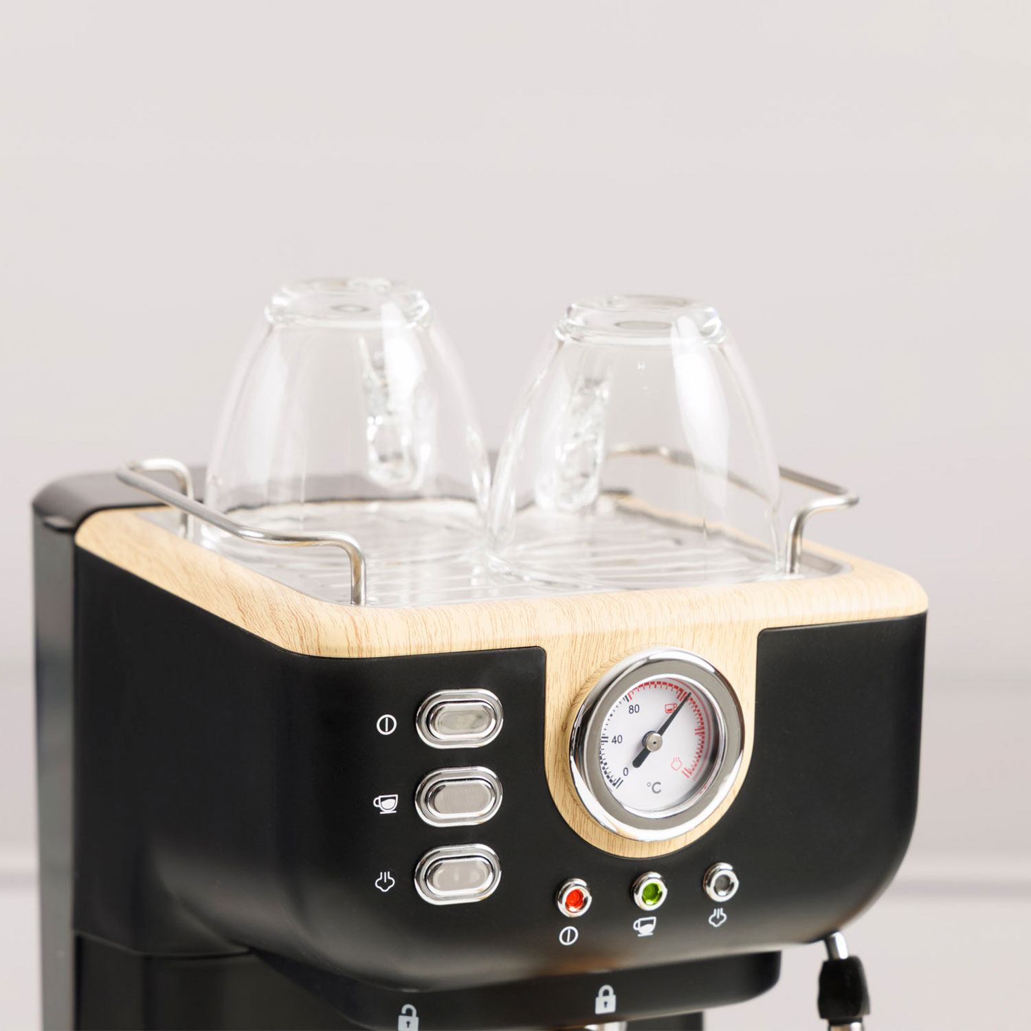 Una cafetera espresso negra con detalles de madera y dos tazas de cristal.