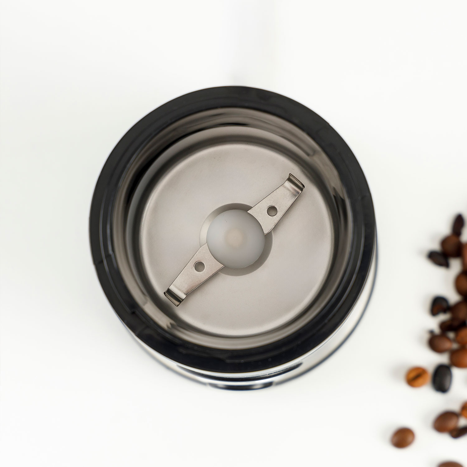 Un molinillo de café eléctrico con cuchillas y granos de café sobre fondo blanco.