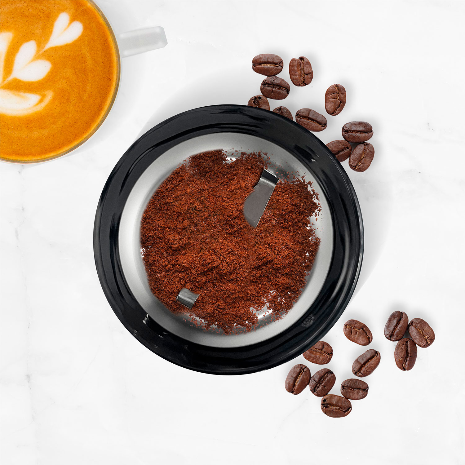 Molinillo de café con polvo, granos de café y café con arte latte sobre fondo de mármol.