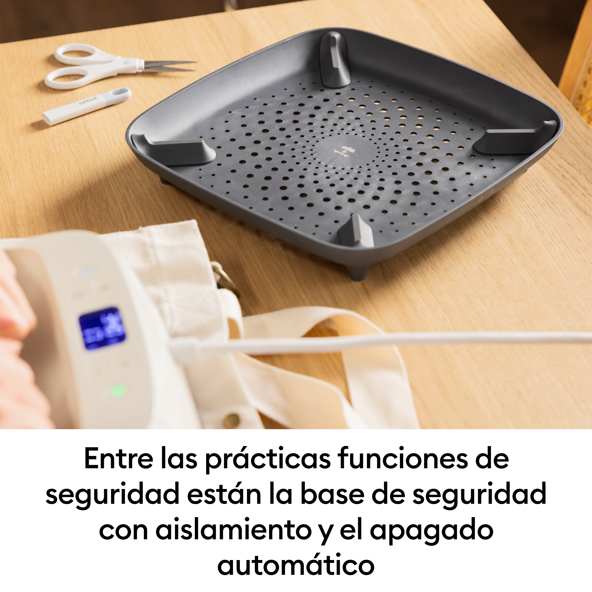 Tijeras blancas y herramienta Cricut junto a una prensa de calor gris.