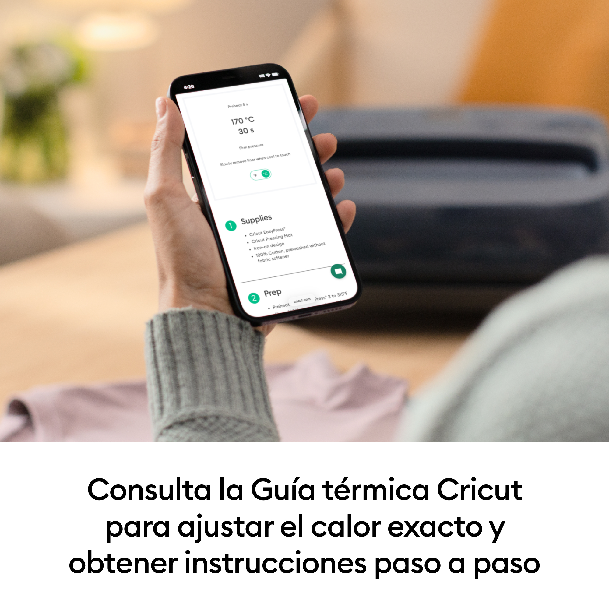 Una mano sostiene un smartphone que muestra instrucciones para una Cricut EasyPress.