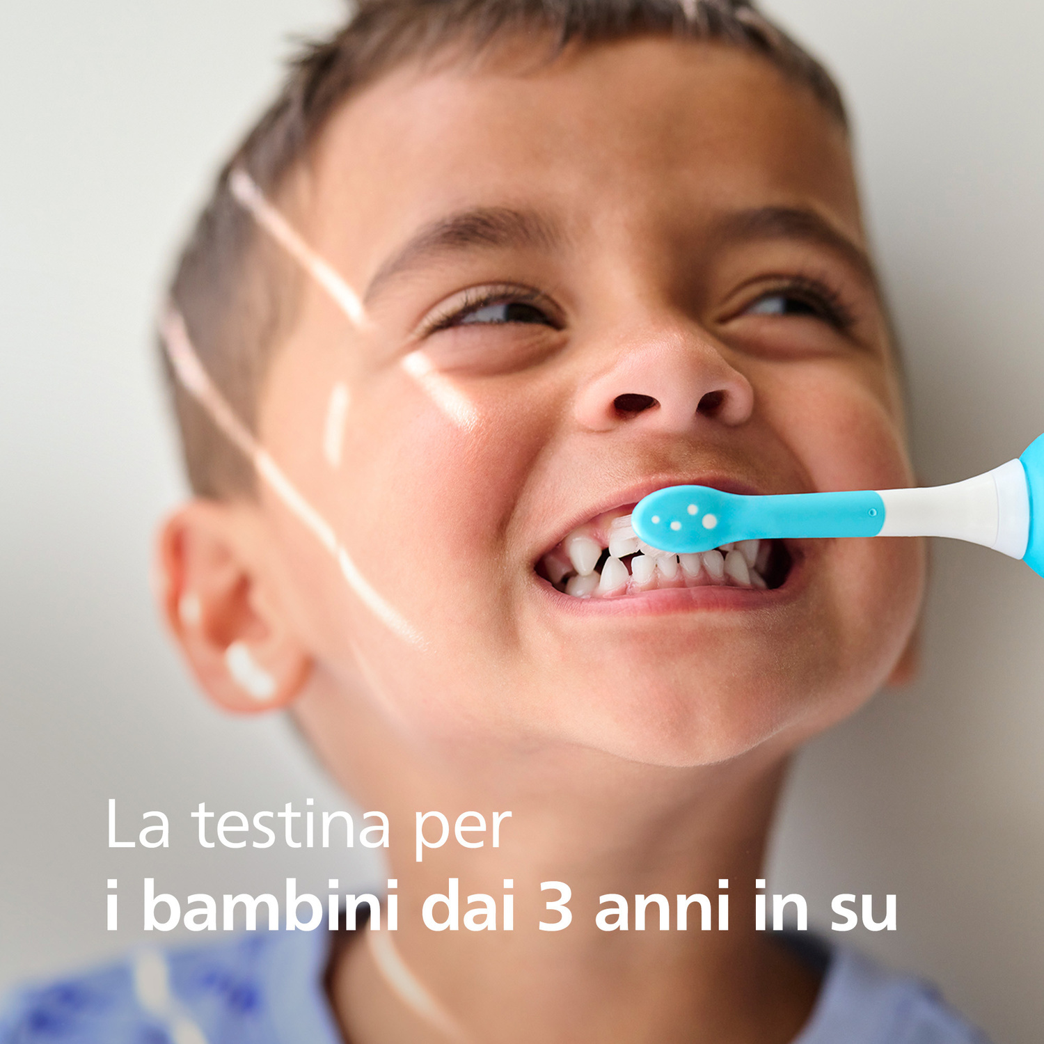 Un bambino si lava i denti con uno spazzolino elettrico blu.
