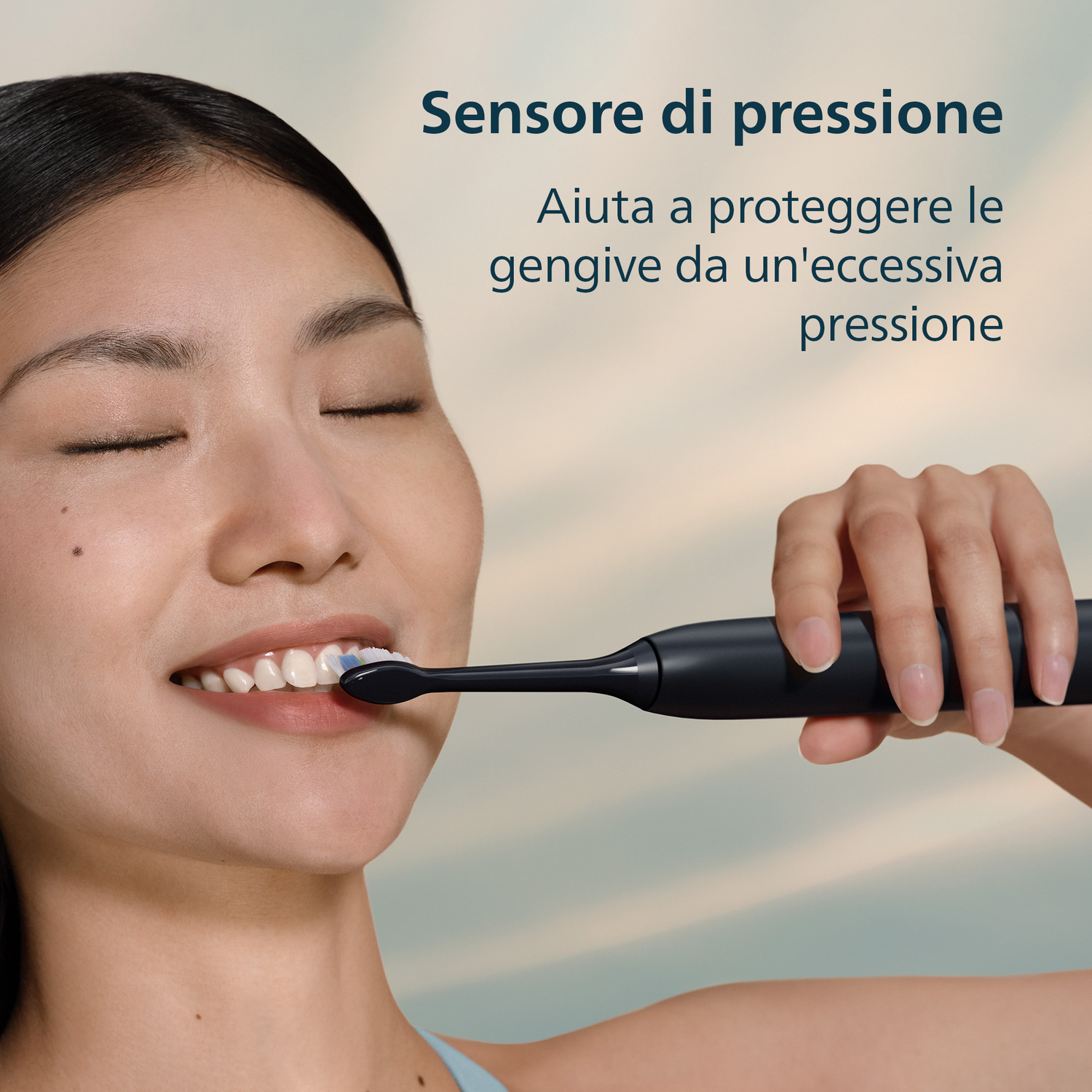 Una donna si lava i denti con uno spazzolino elettrico nero.