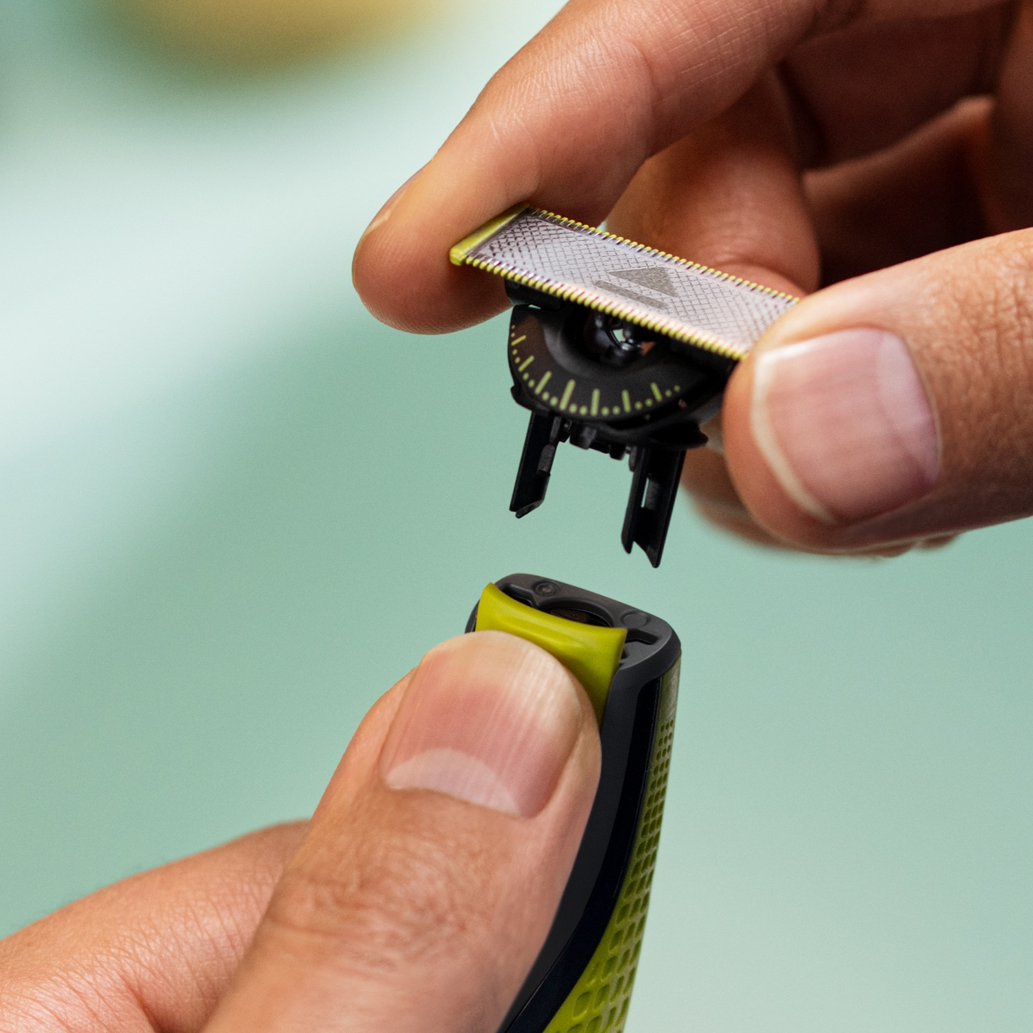 Mani che assemblano una testina del rifinitore con bordo giallo e dettagli neri.