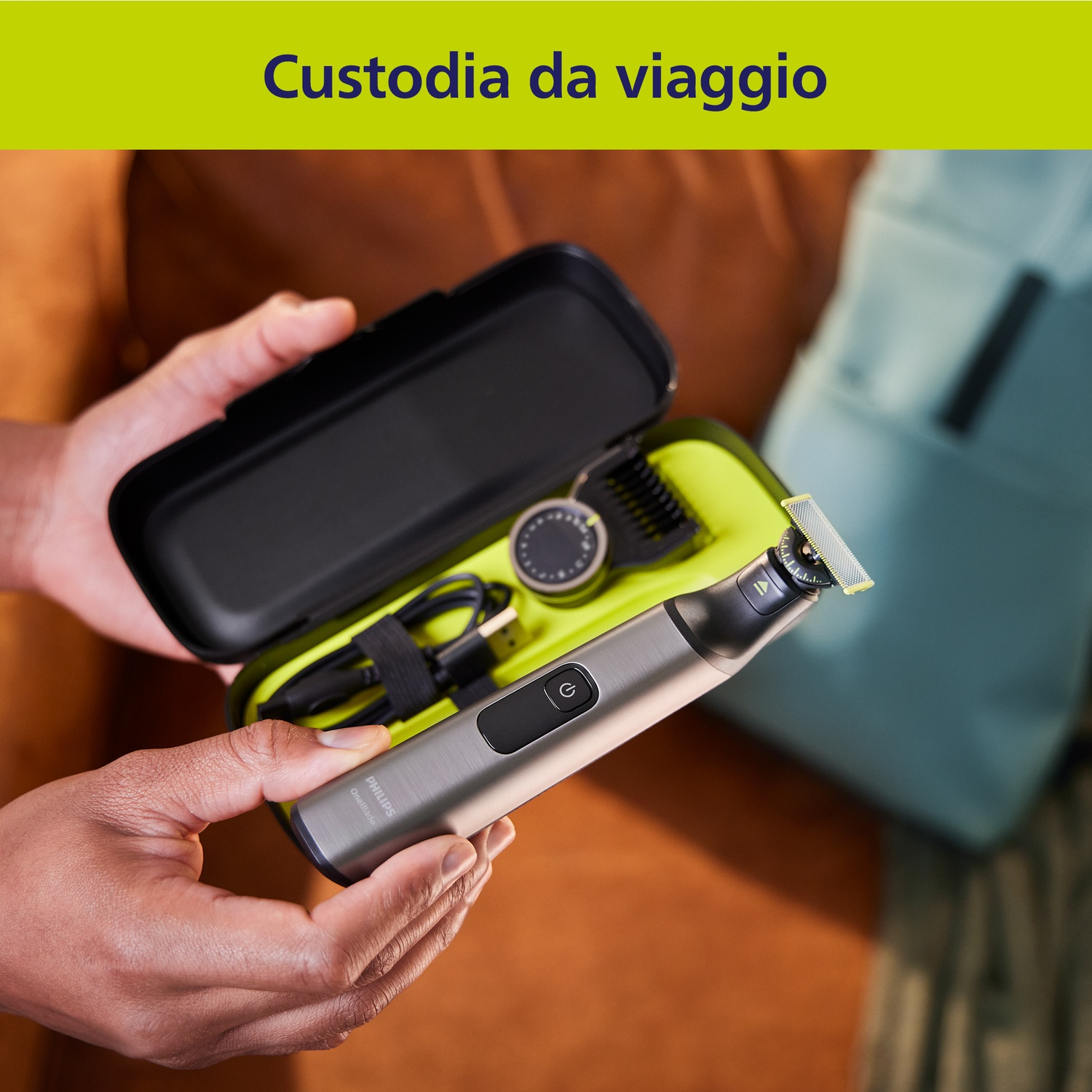 Un uomo tiene un rifinitore Philips OneBlade argentato con accessori in una custodia nera.