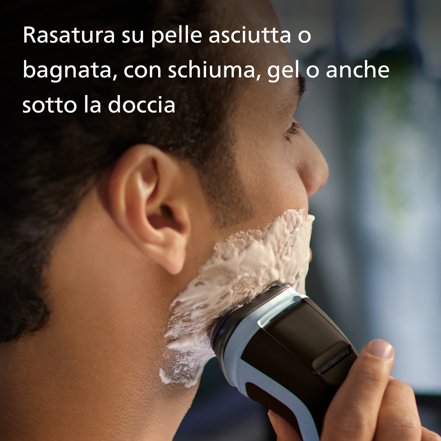 Uomo si rade il viso con rasoio elettrico e schiuma.