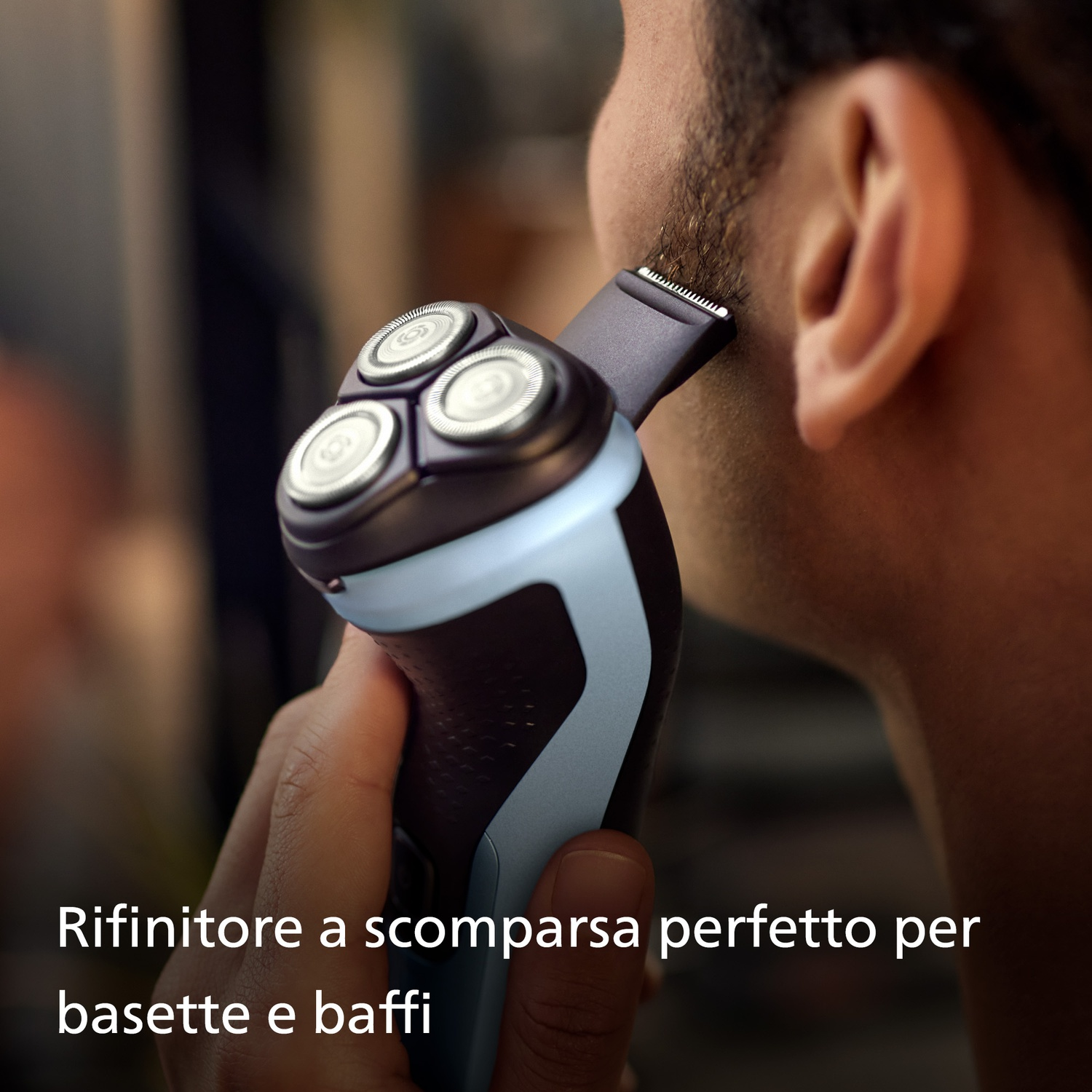 Uomo che rifinisce le basette con un rasoio. Rasoio grigio scuro con impugnatura chiara.