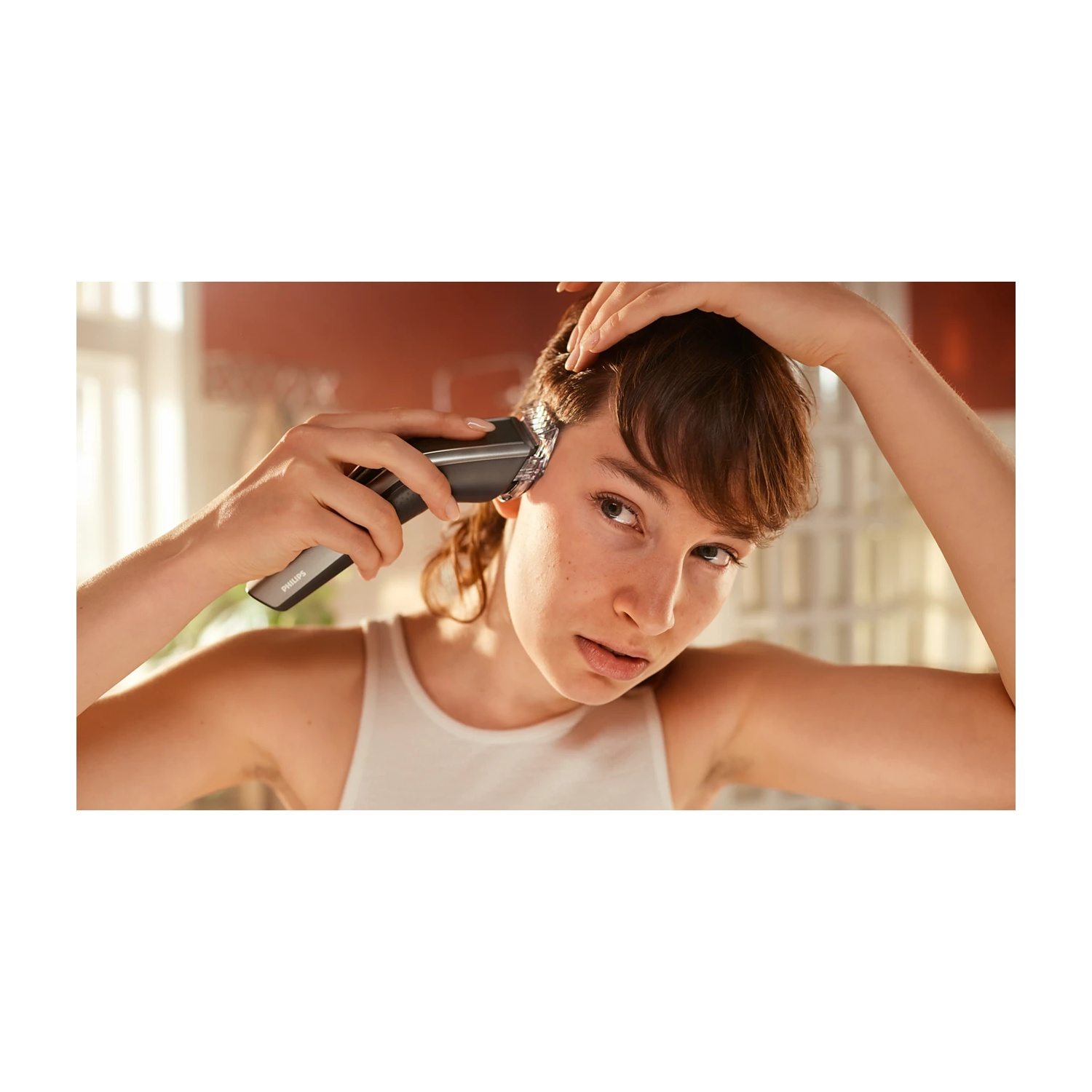 Una donna si taglia i capelli con un rifinitore Philips. Indossa un top bianco.