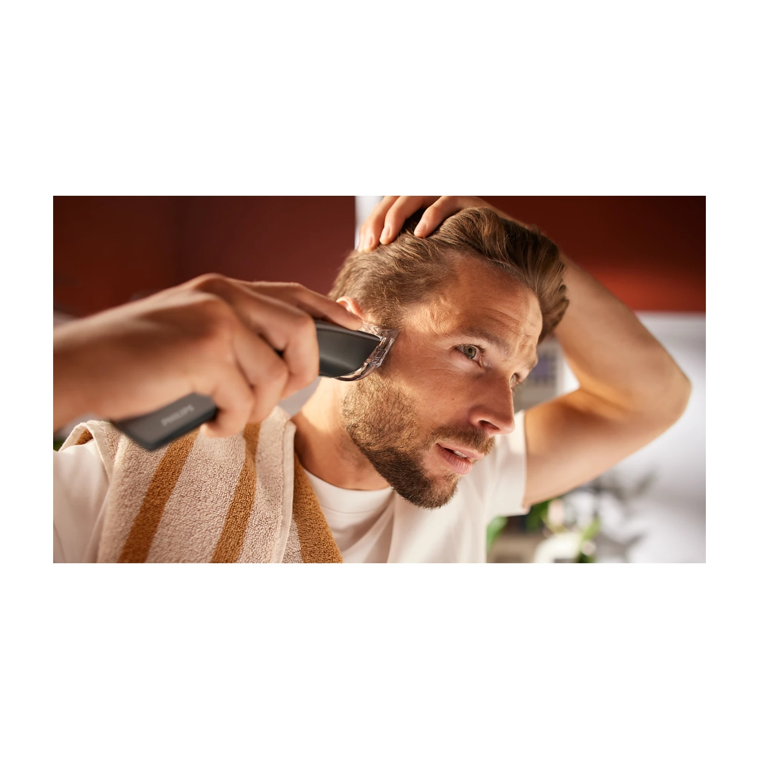 Uomo si taglia la barba con un trimmer elettrico, una mano tiene il dispositivo.