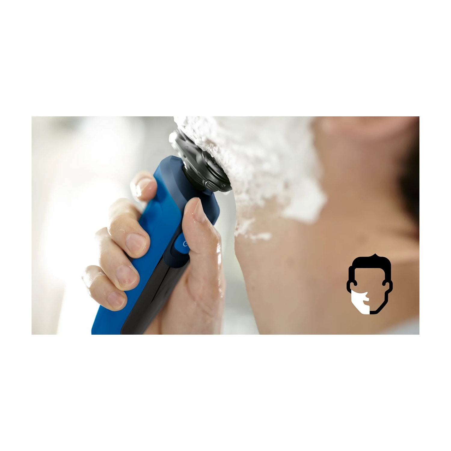 Uomo che si rade con un rasoio elettrico blu e schiuma da barba.