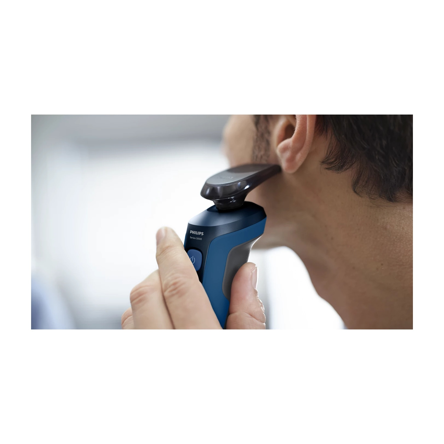 Un uomo si rade il viso con un rasoio Philips Serie 5000 blu.