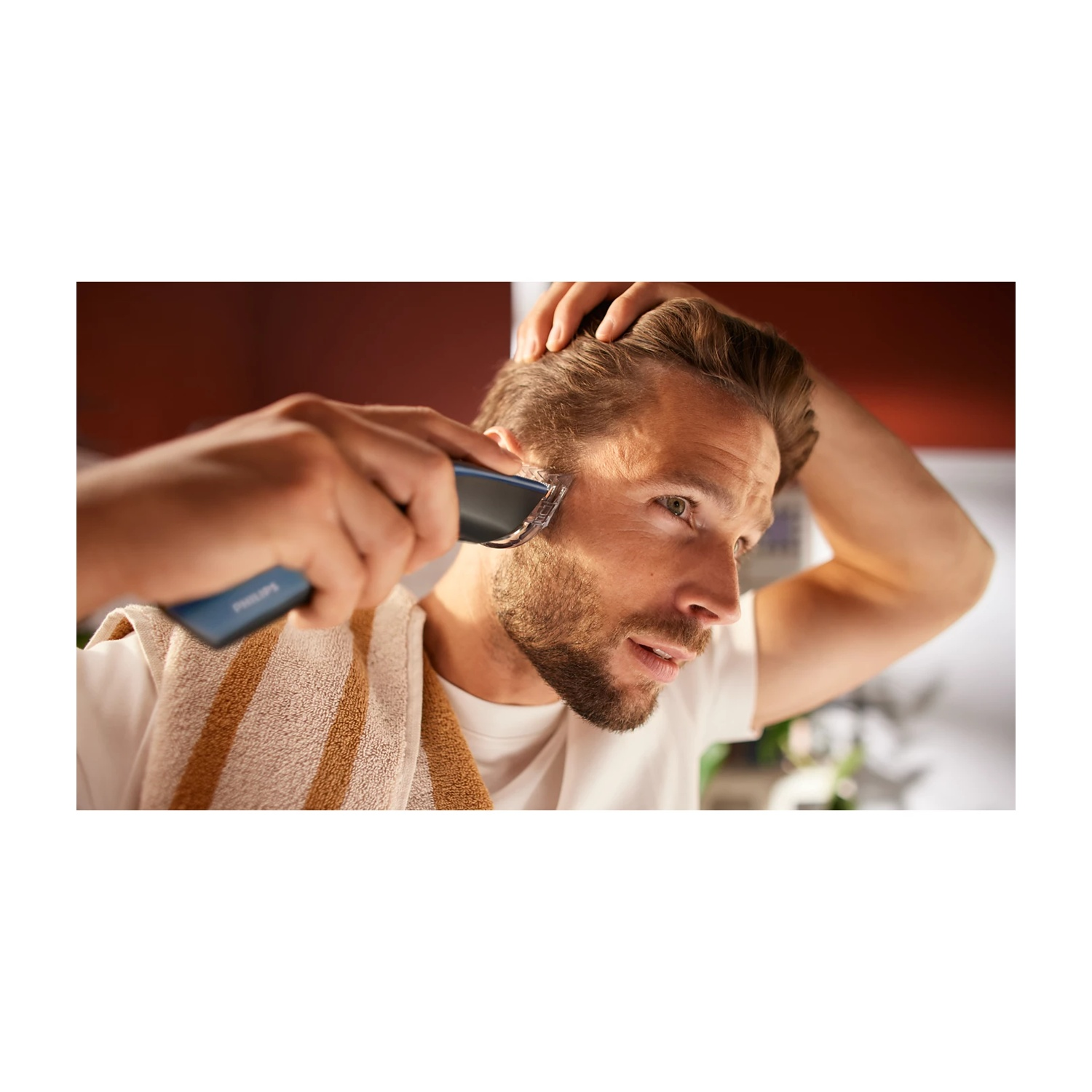 Un uomo si rade la barba con un rifinitore Philips davanti a uno specchio.