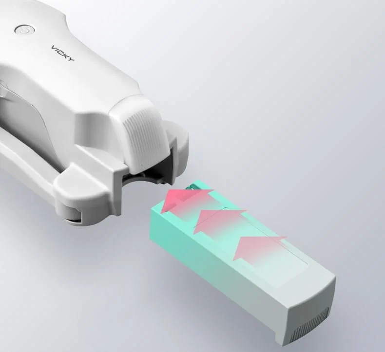 Biały korpus drona z wyjmowaną baterią, zaznaczony różowymi strzałkami.