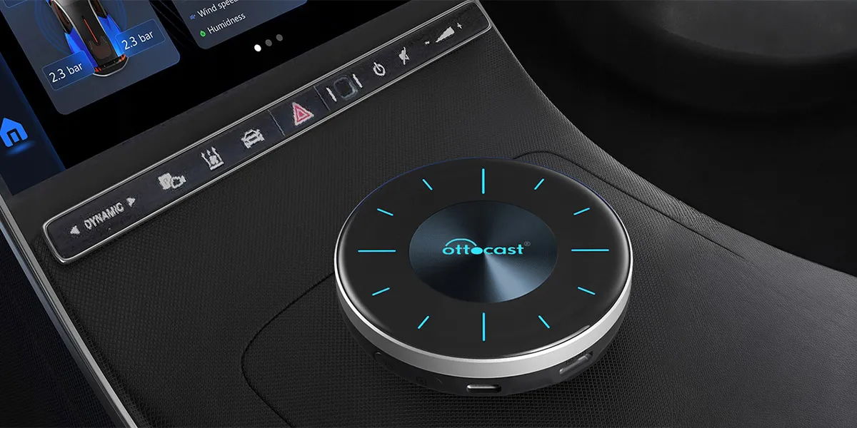 Czarny pokrętło Ottocast z niebieskimi światłami na desce rozdzielczej obok ekranu.