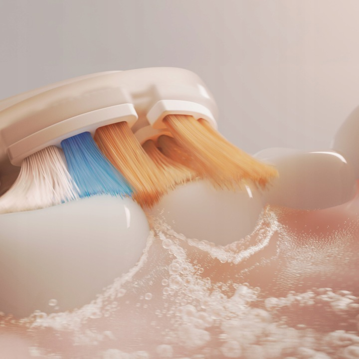 Zbliżenie szczoteczki elektrycznej z włosiem czyszczącym zęby, tworzącym pianę.