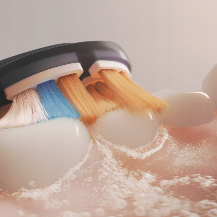 Szczoteczka elektryczna z pomarańczowymi i niebieskimi włoskami na białym zębie.