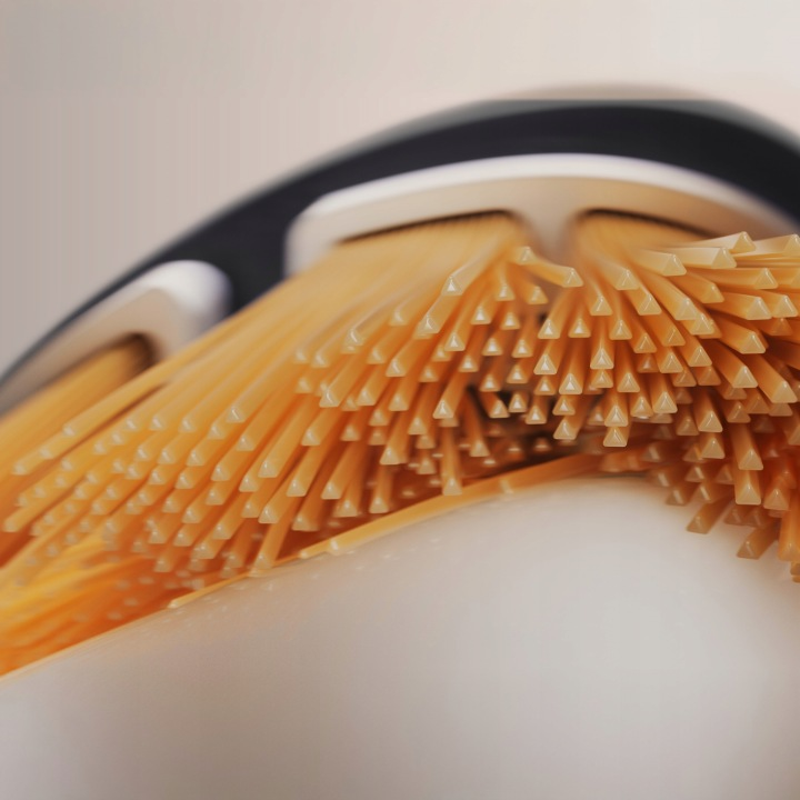 Zbliżenie makaronu spaghetti przechodzącego przez szczotkę z białymi i czarnymi uchwytami.