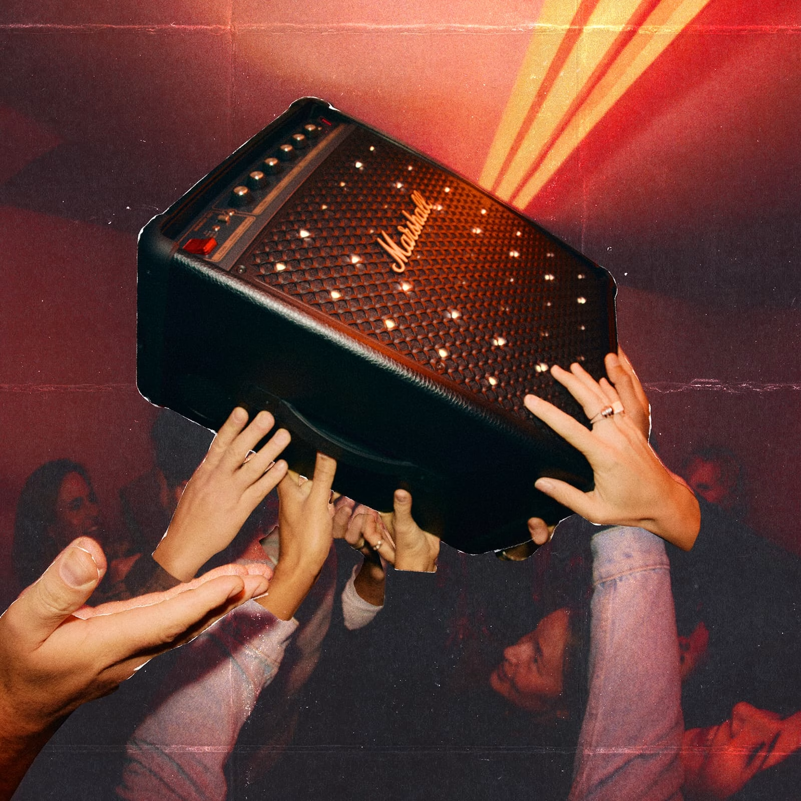 Mani tengono un amplificatore Marshall sopra una folla sotto luci rosse.
