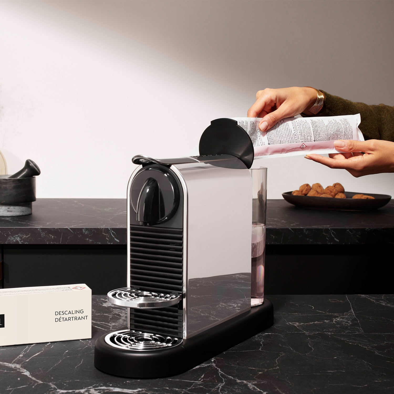 A person is adding descaler to a coffee machine's water tank.