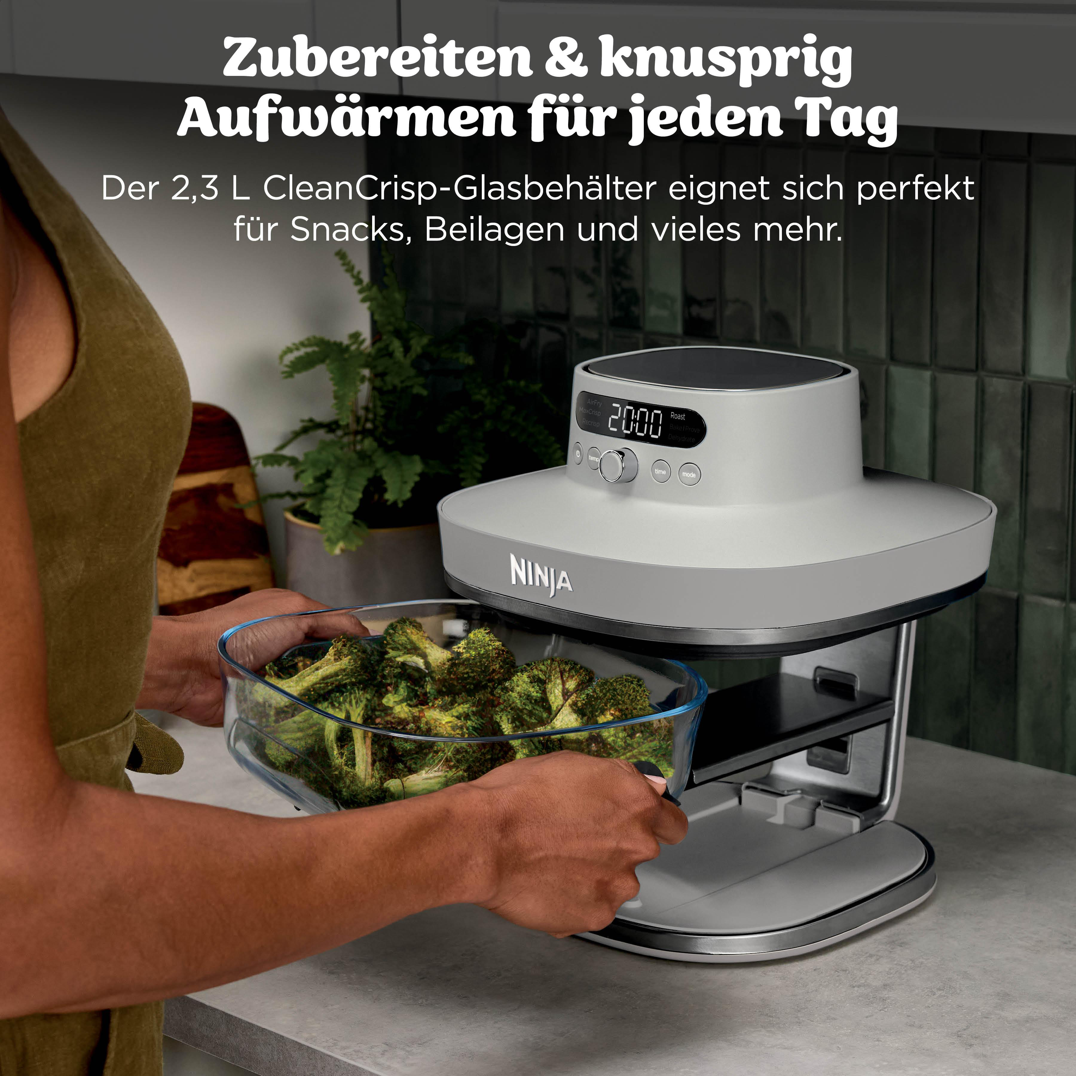 Eine Person legt Brokkoli in einen Ninja Airfryer mit einem Glasbehälter.