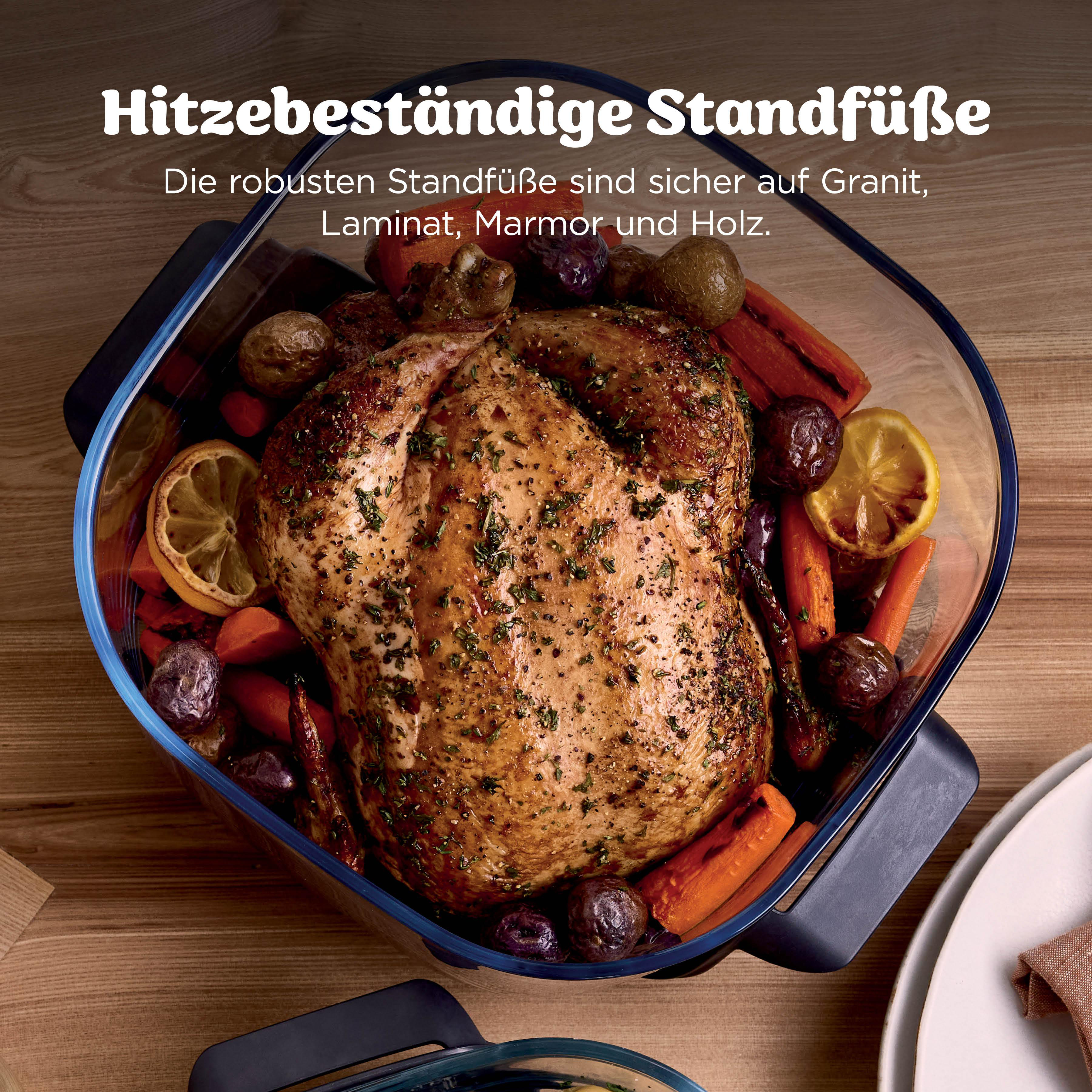 Ein gebratenes Hähnchen mit Kartoffeln, Karotten und Zitronenscheiben in einer Glasschale.
