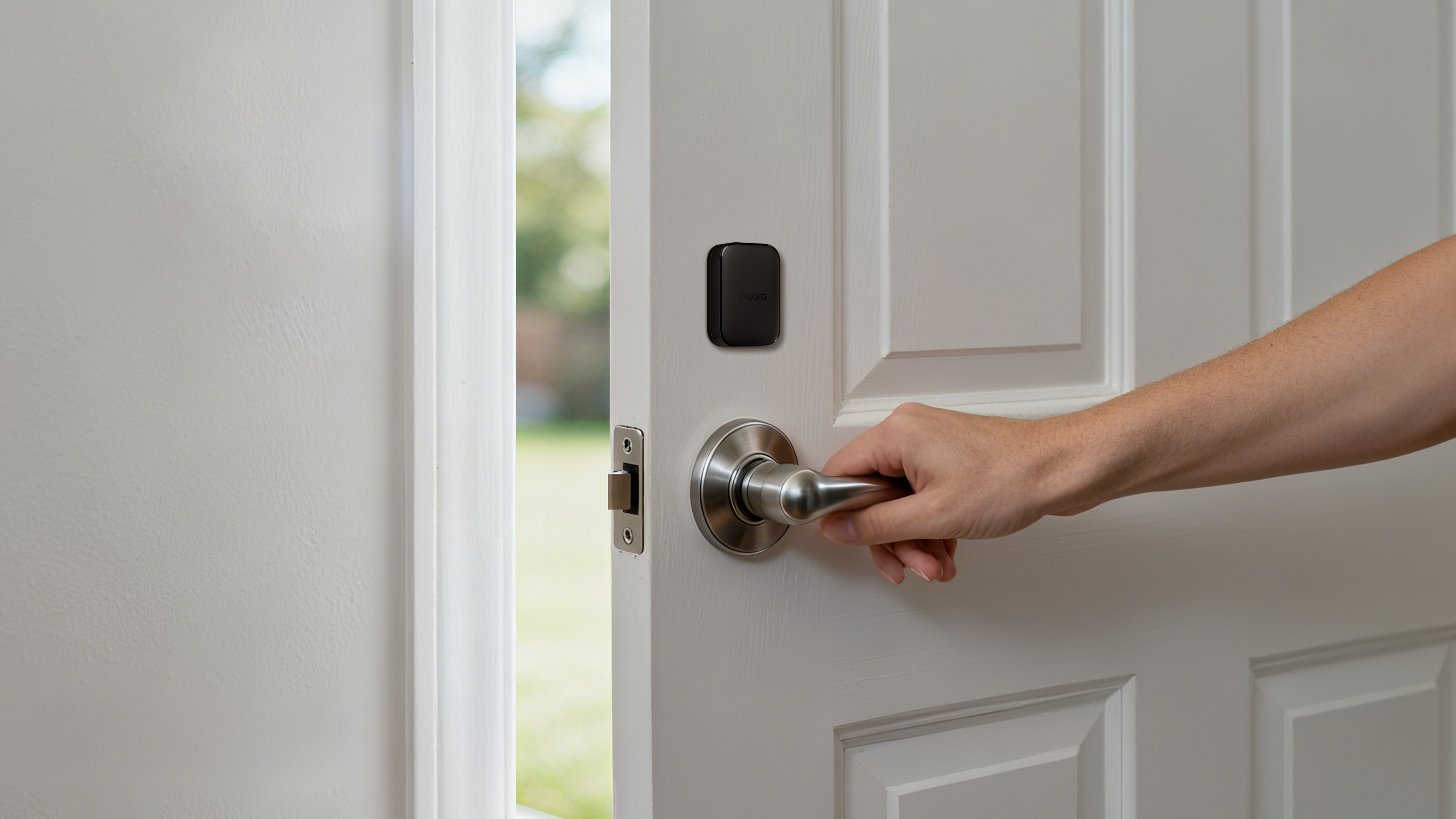 Hand dreht silbernen Türgriff einer weißen Tür mit schwarzem Smart Lock.