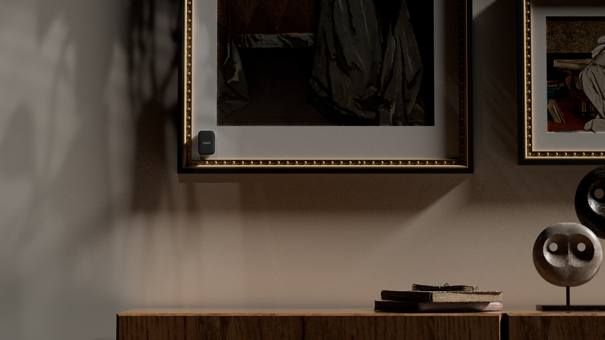 Ein kleiner schwarzer Sensor hängt an einem gerahmten Bild über einem Holzschrank.