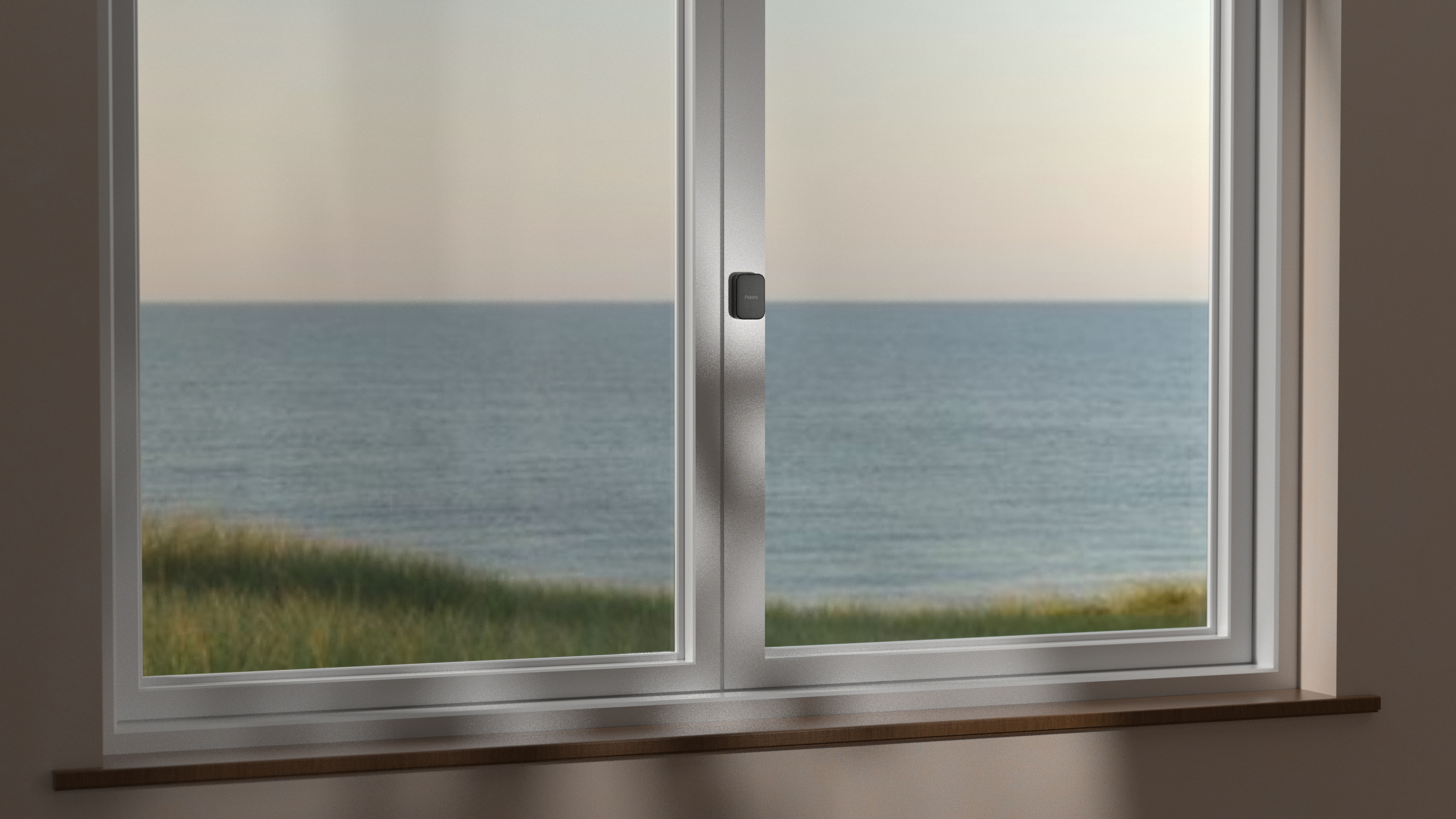 Fenster mit Blick aufs Meer und Grasland bei Dämmerung.