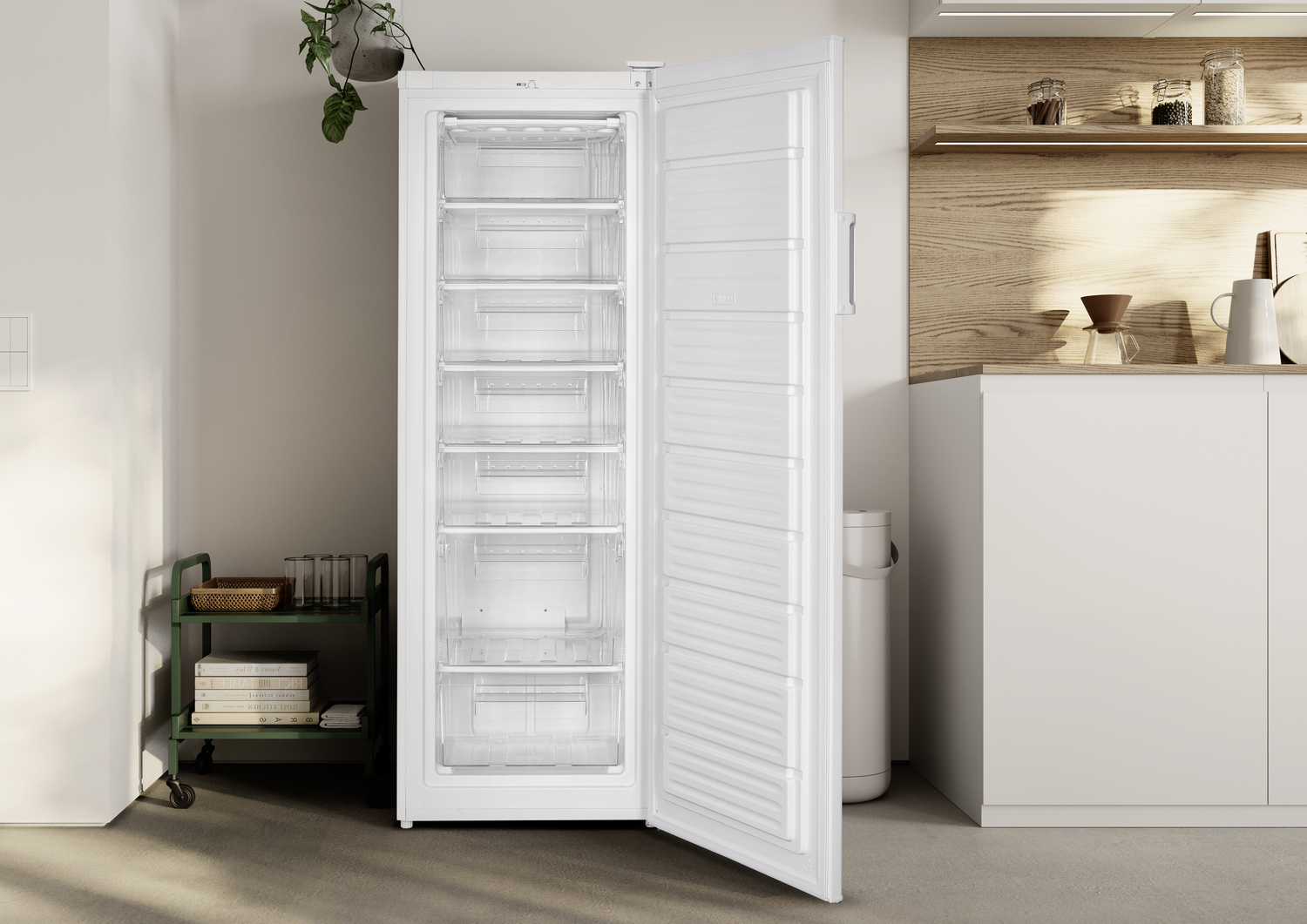 Congelador blanco abierto con cajones transparentes, junto a gabinetes de cocina y un carrito verde.