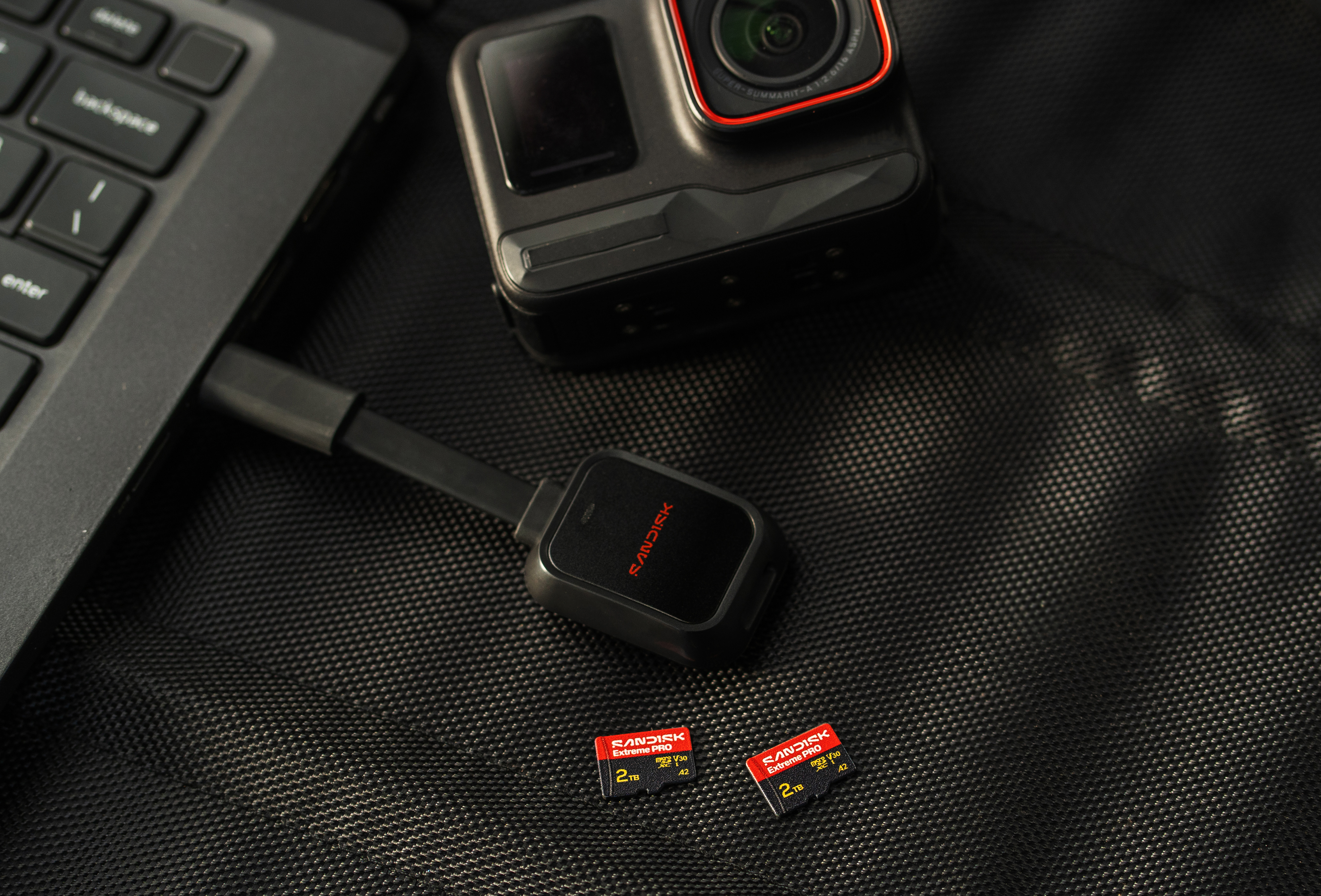 GoPro, SD-Kartenleser und 2TB SD-Karten liegen neben einem Laptop.