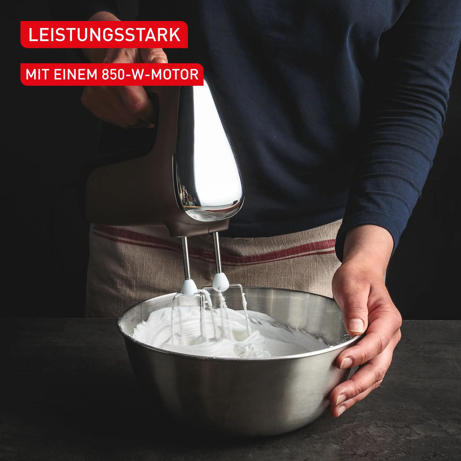 Handmixer schlägt weiße Masse in Edelstahlschüssel.