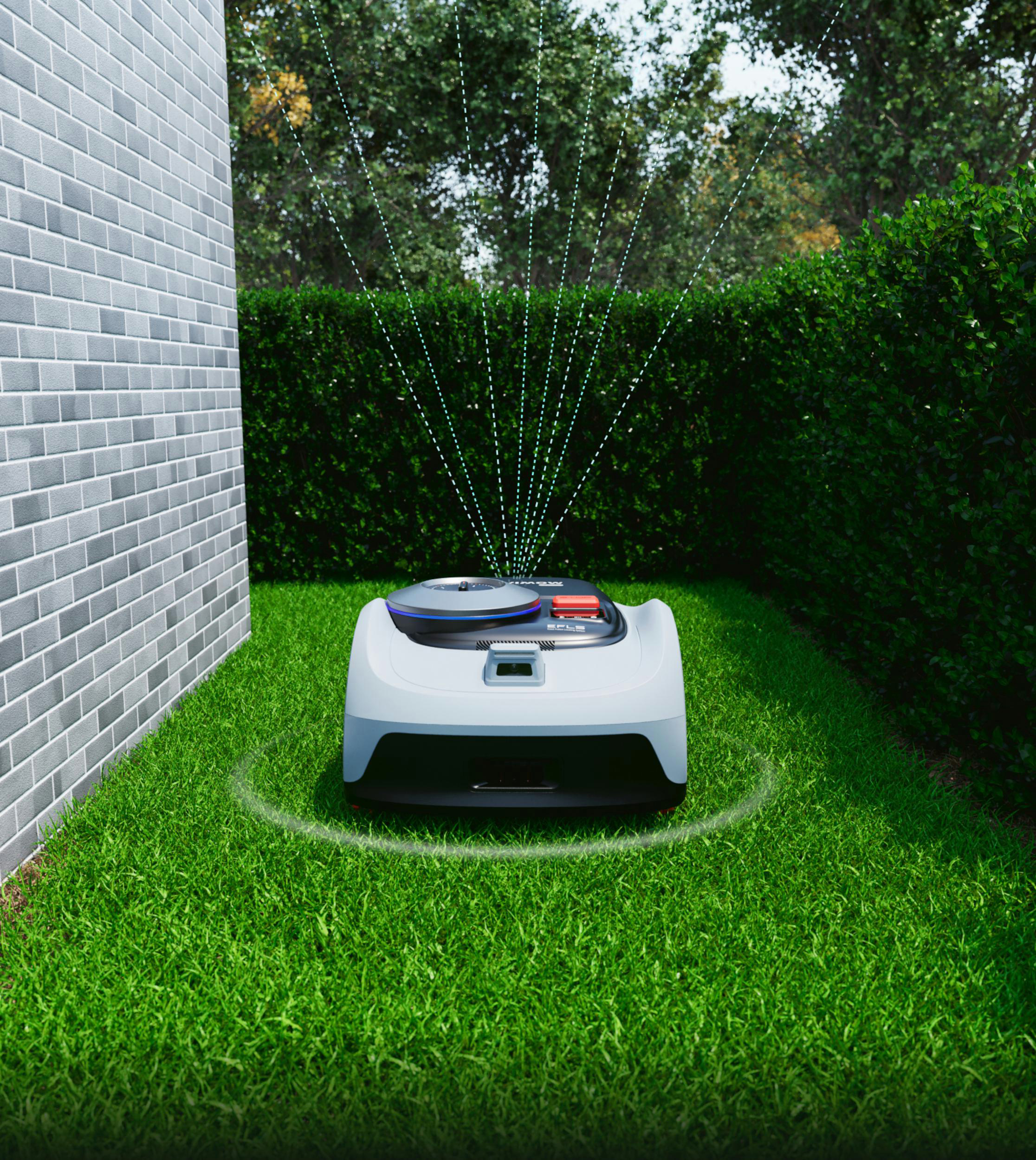 Ein weißer Mähroboter mäht auf einem grünen Rasen neben einer Ziegelwand.