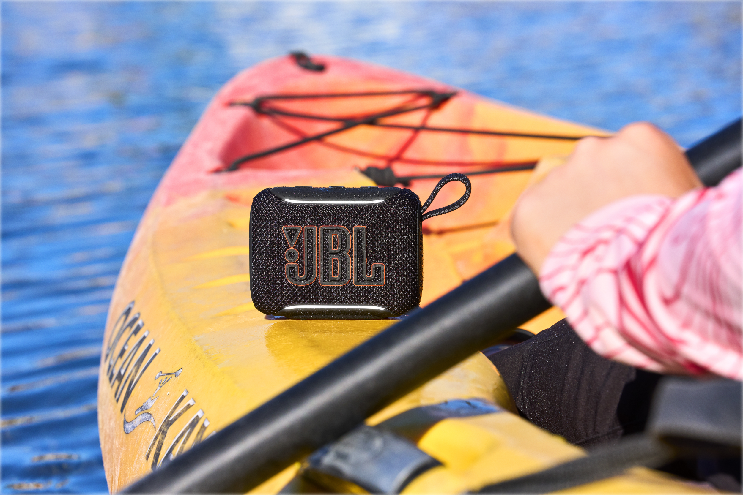 Schwarzer JBL-Lautsprecher auf einem gelben Kajak im blauen Wasser.