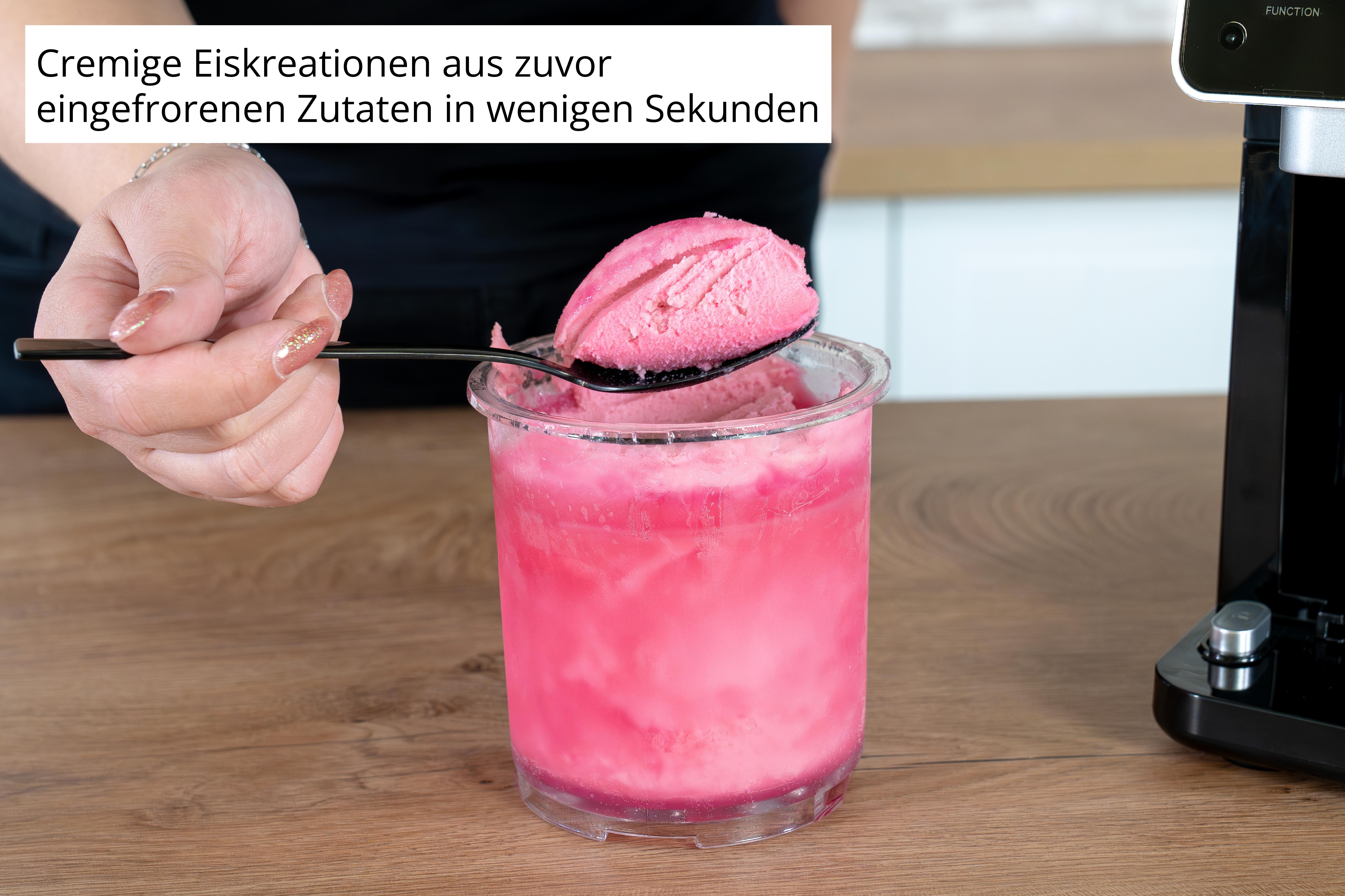 Eine Hand mit glitzernden Nägeln hält einen Löffel mit rosa Eiscreme über einem Behälter.