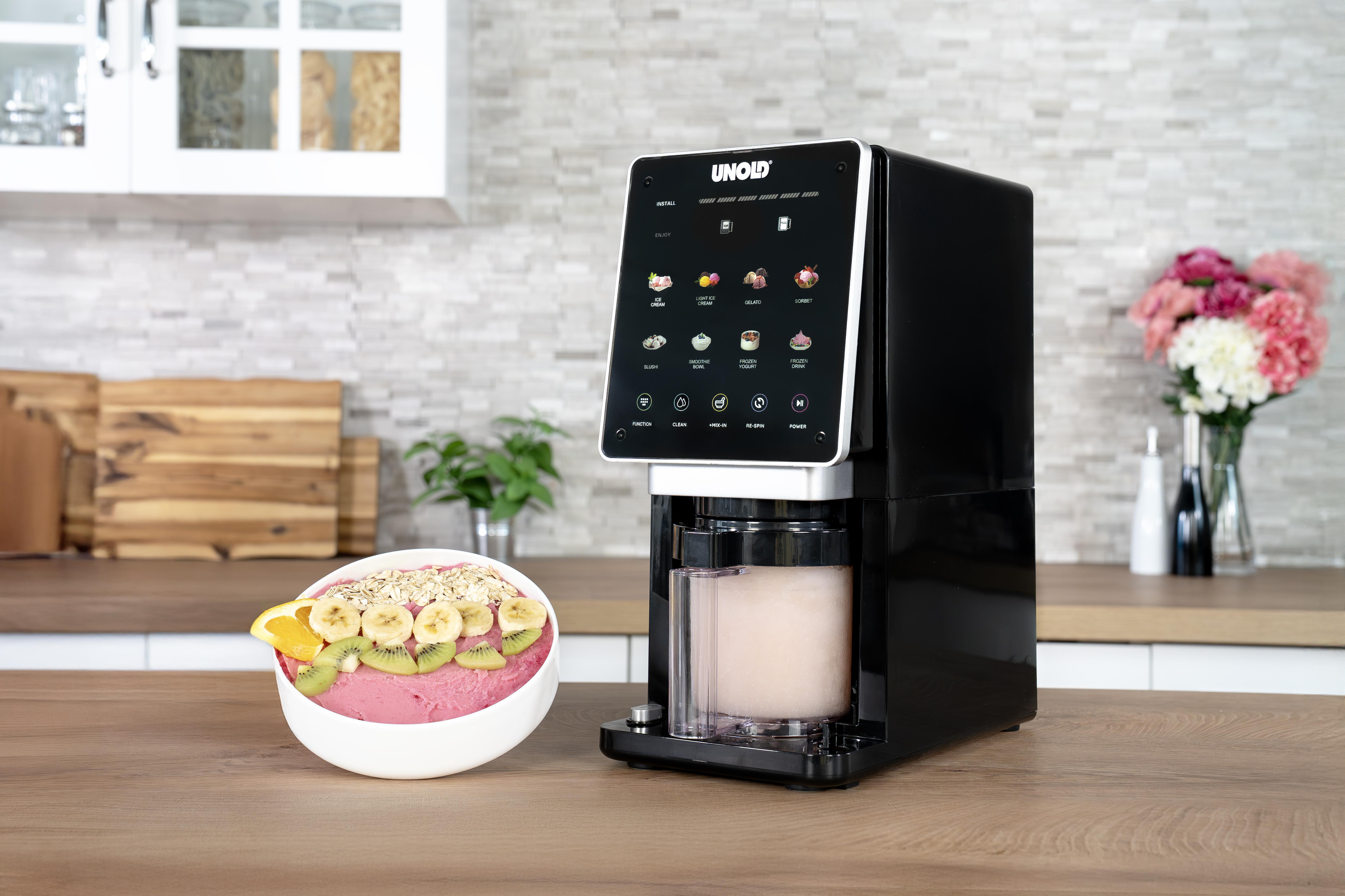 Ein schwarzes Gerät mit Touchscreen neben einer Schüssel gefüllt mit gefrorenem Joghurt und Obst.
